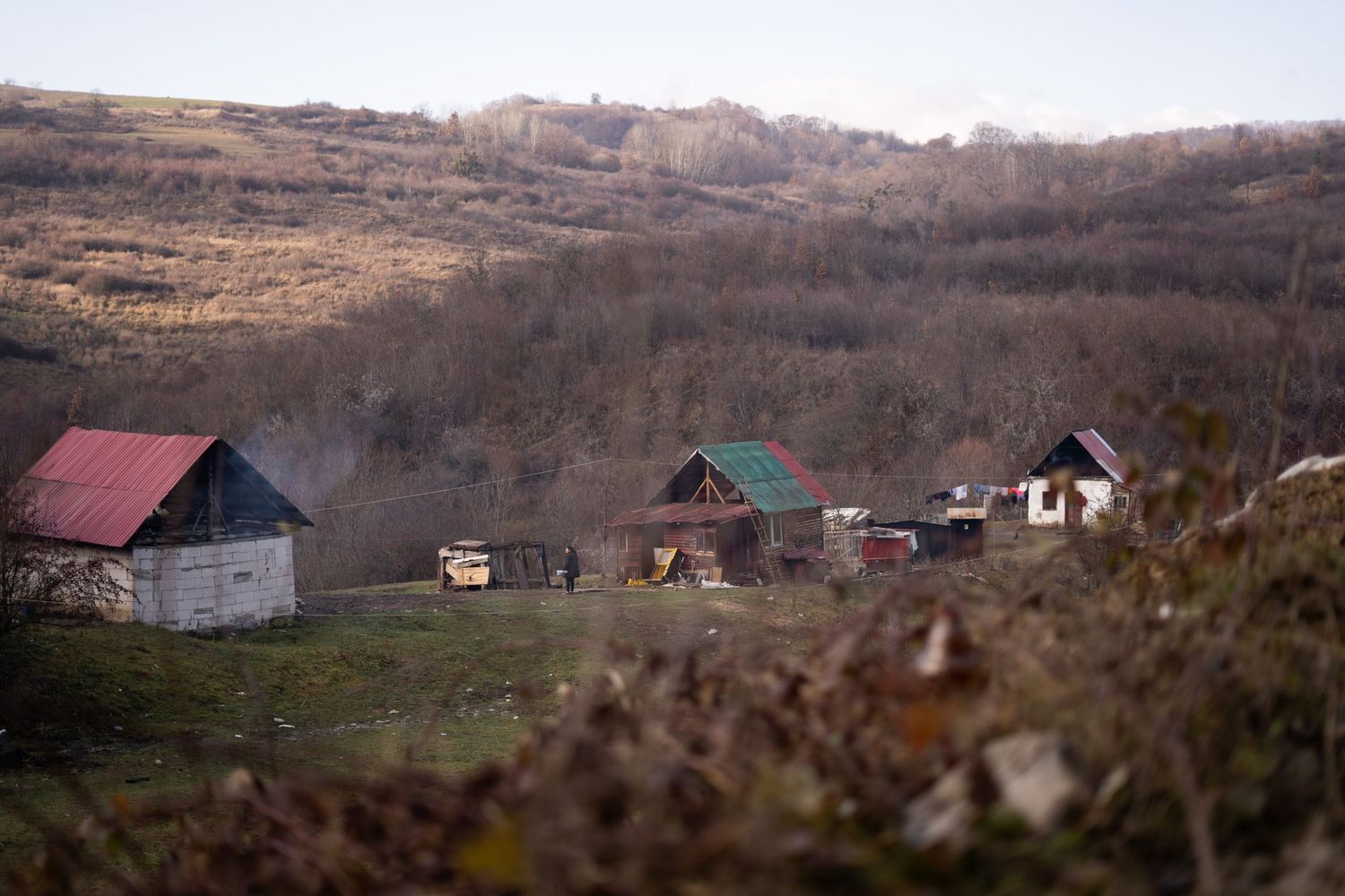 Rural landscape with scattered houses and red roofs nestled in a winter hillside.