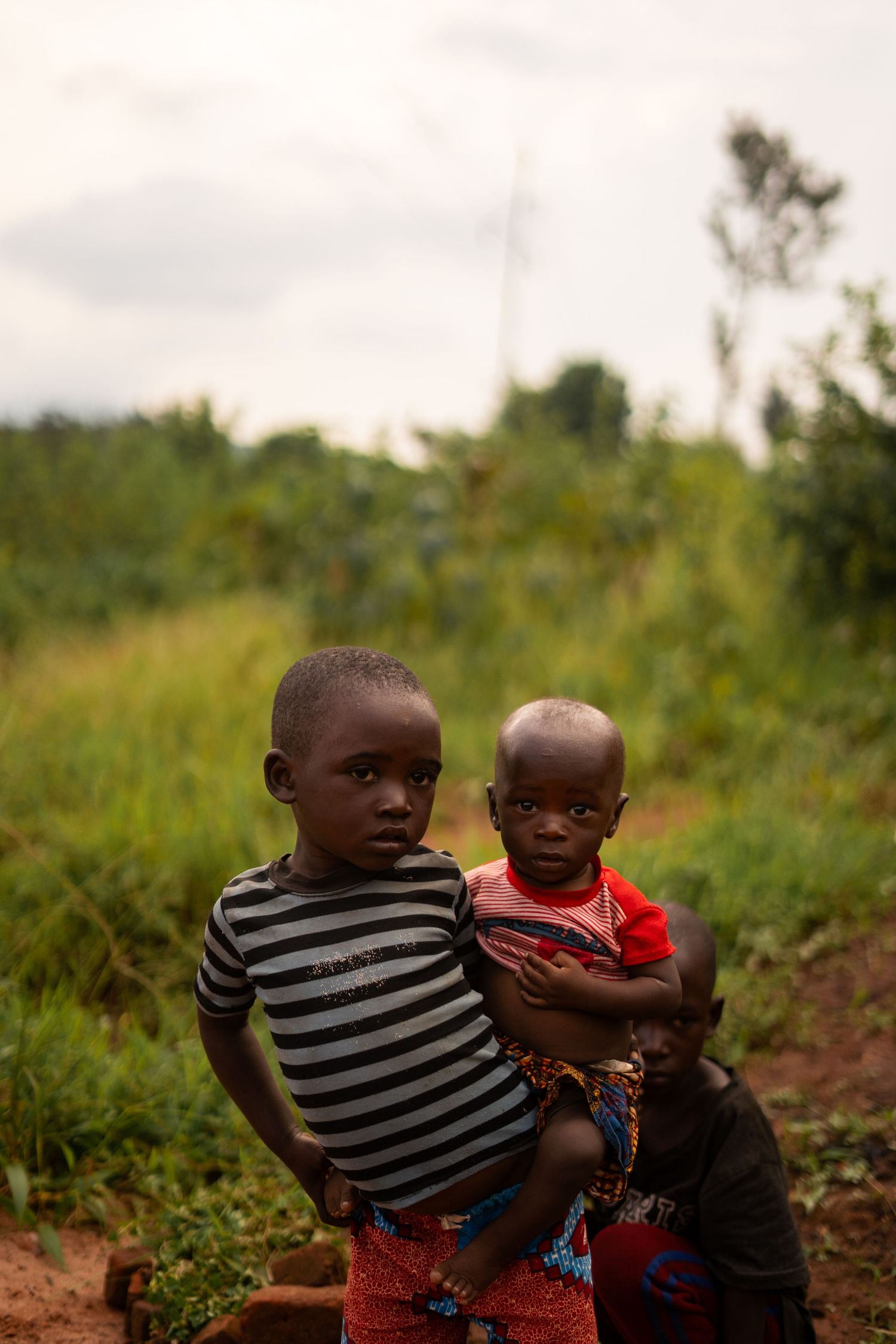 Young children in casual clothing standing together in a grassy field.
