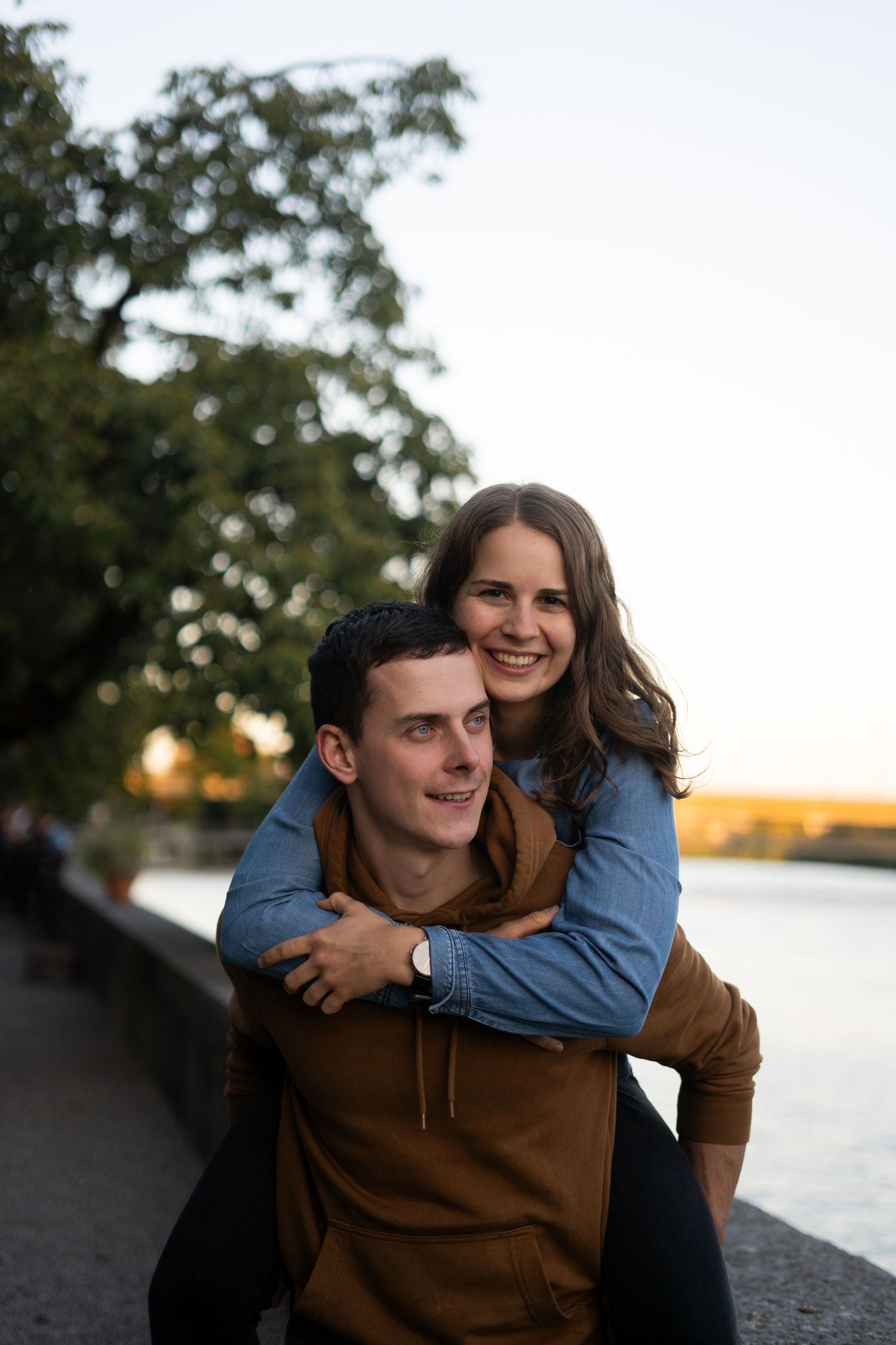 Playful piggyback moment captured by the water during golden hour.