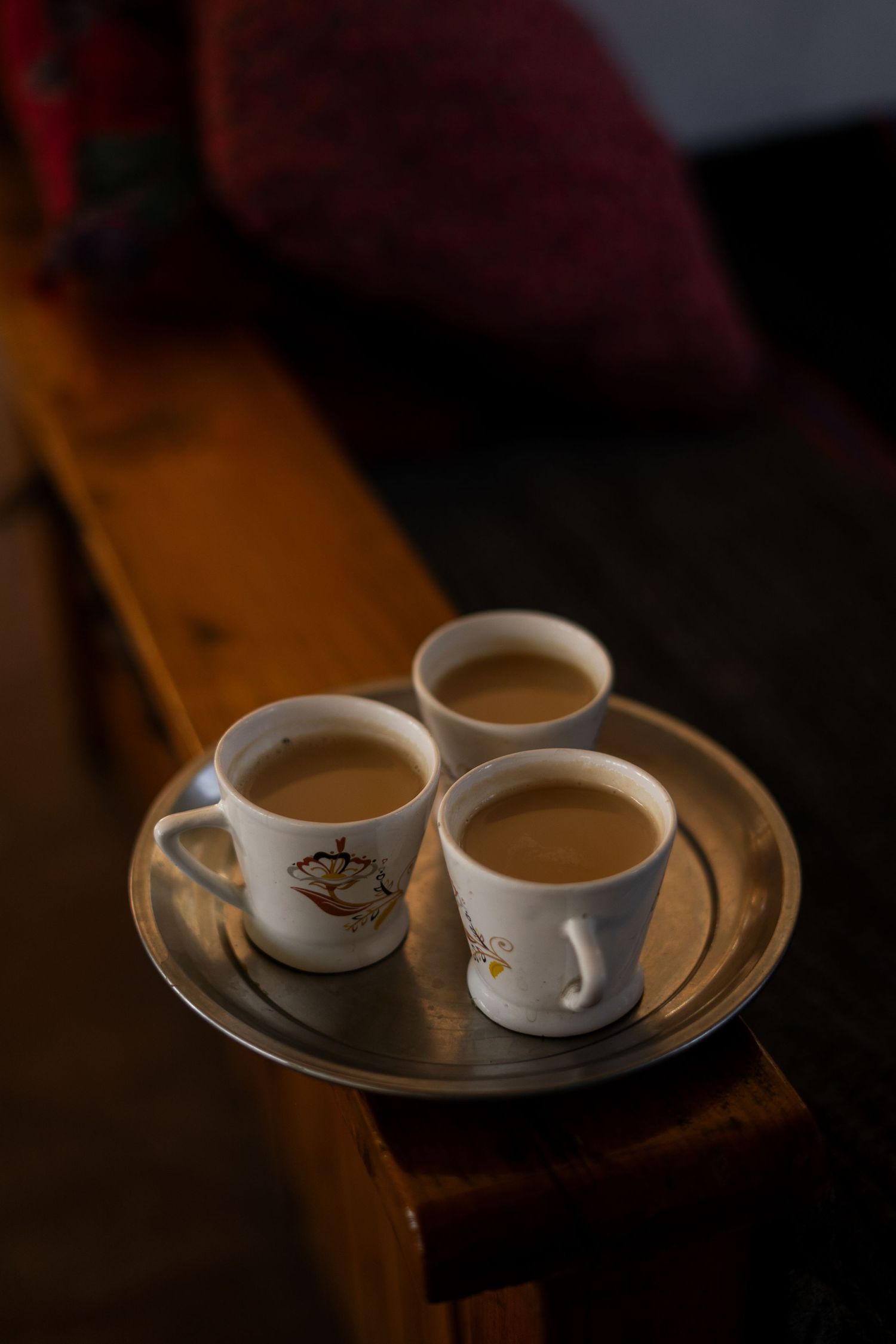 Two cups of chai tea served on a wooden tray in dim lighting.