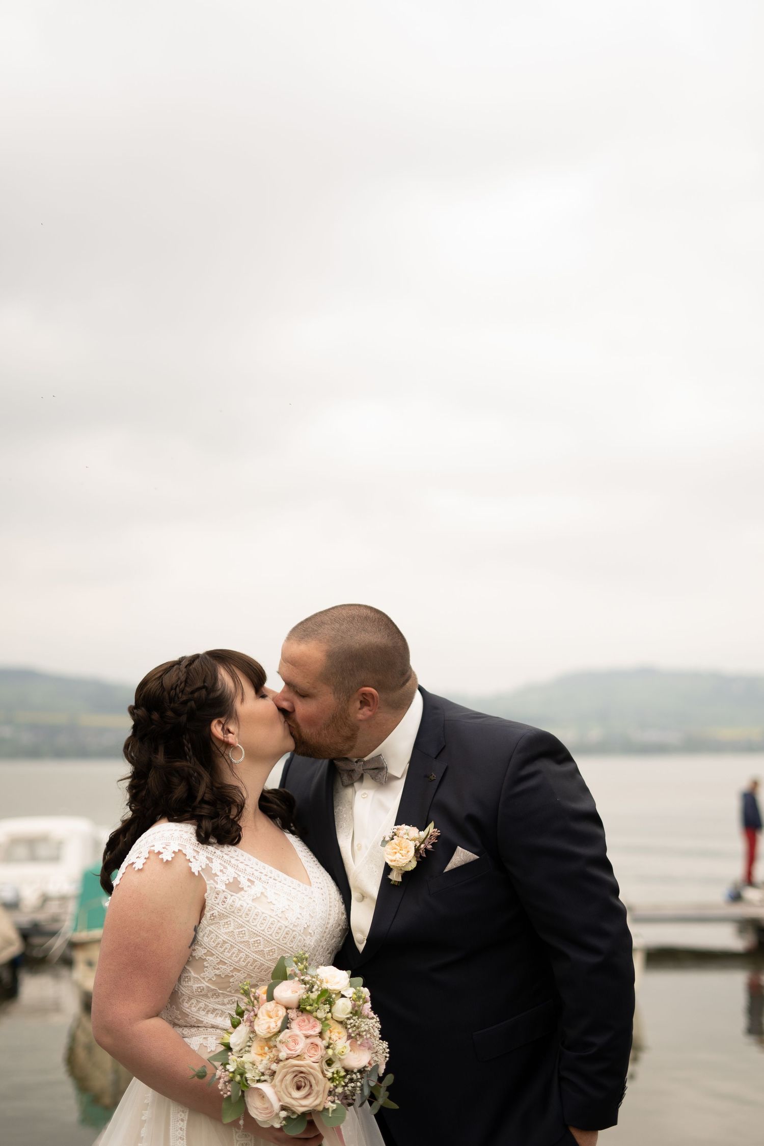 Romantic lakeside wedding portraits with rolling hills and water in the background.