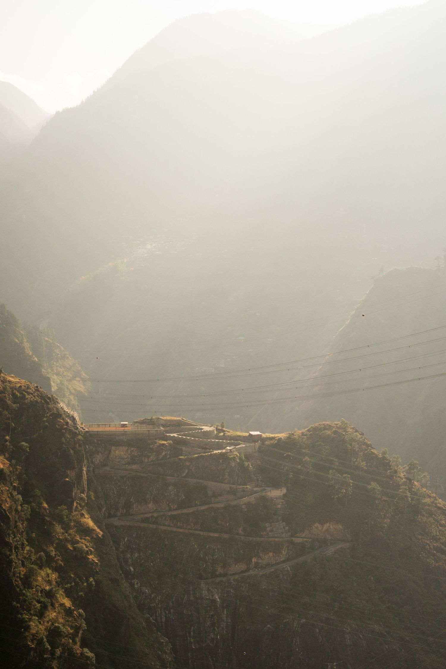 Misty mountain landscape with winding roads carved into steep hillsides.