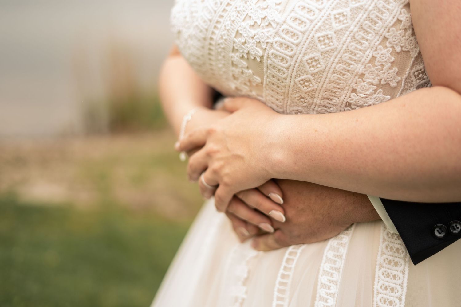 Delicate lace details of a white wedding dress against natural lighting.