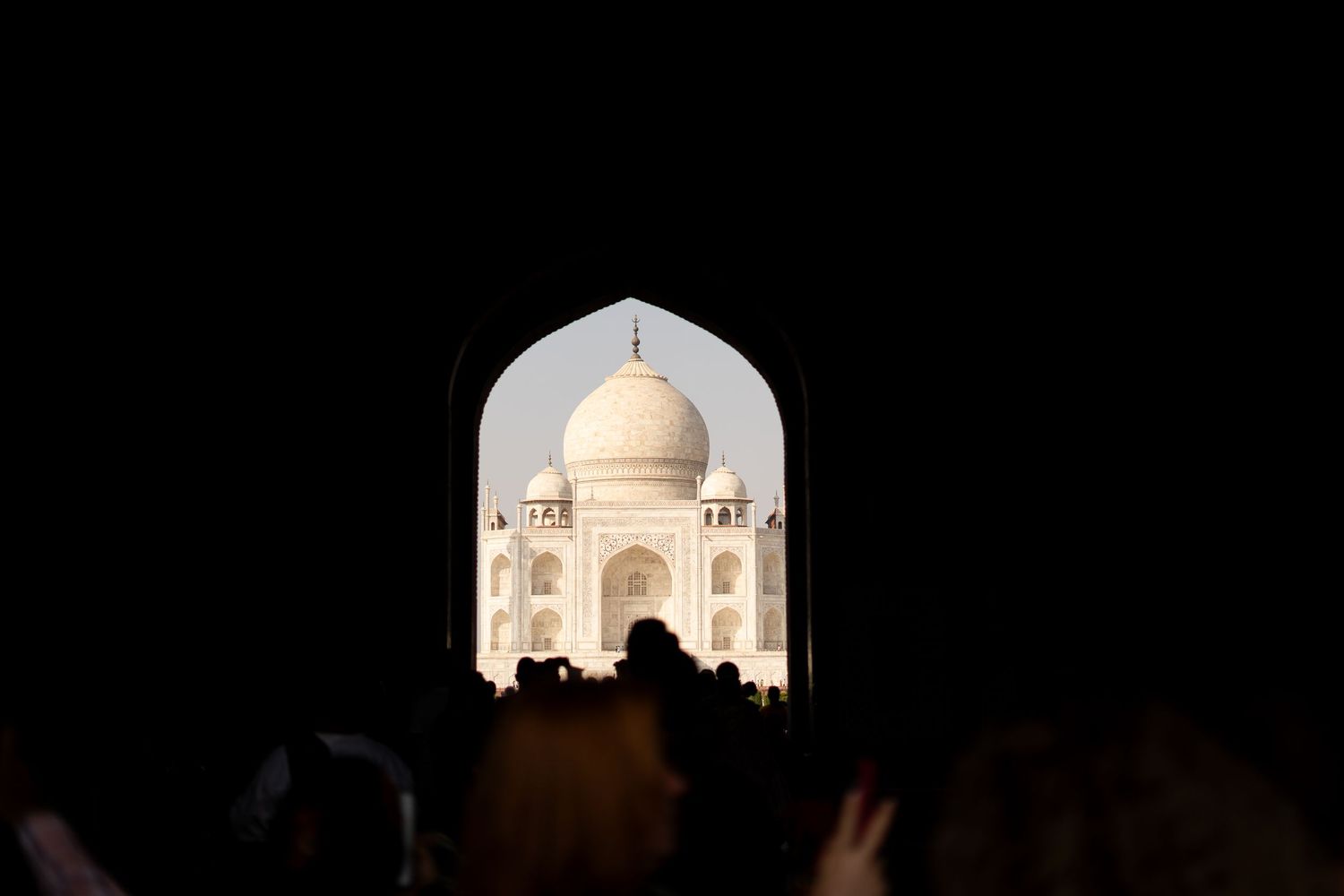 The Taj Mahal silhouetted through an archway against a dark background.