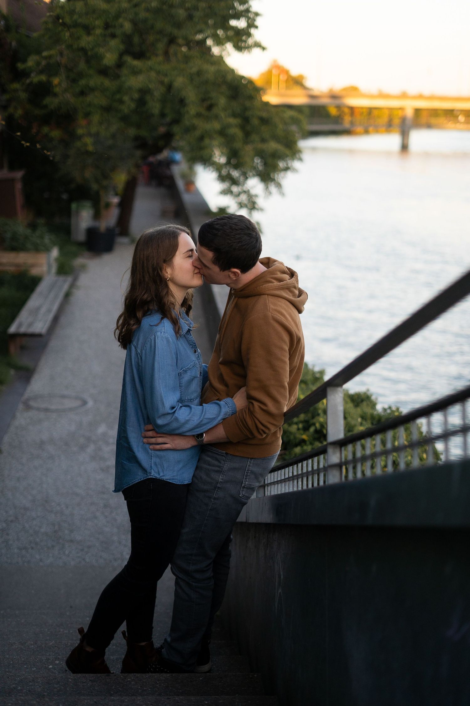 Romantic riverside moment with couple embracing at sunset.