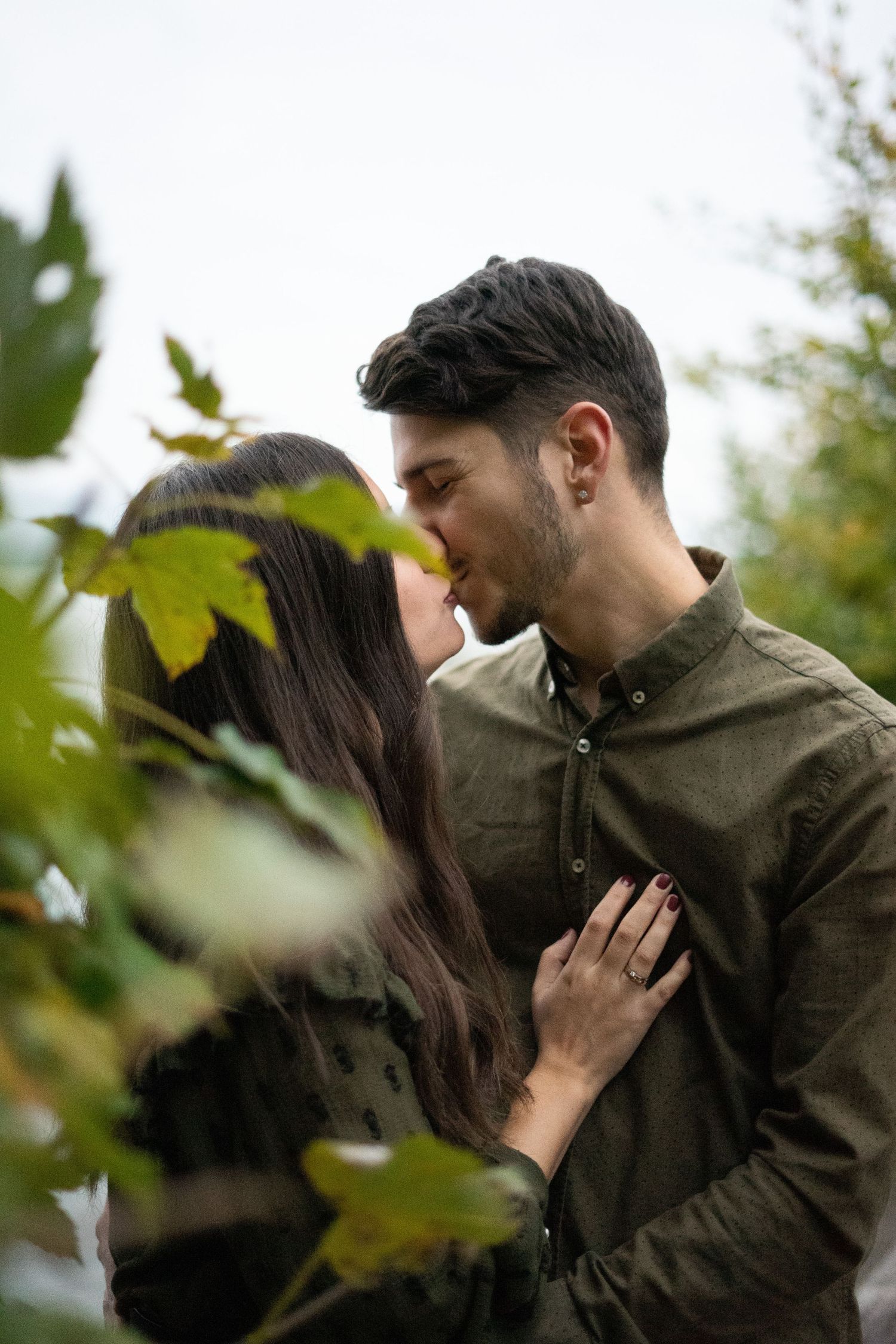 Intimate autumn moments between couple among green leaves.