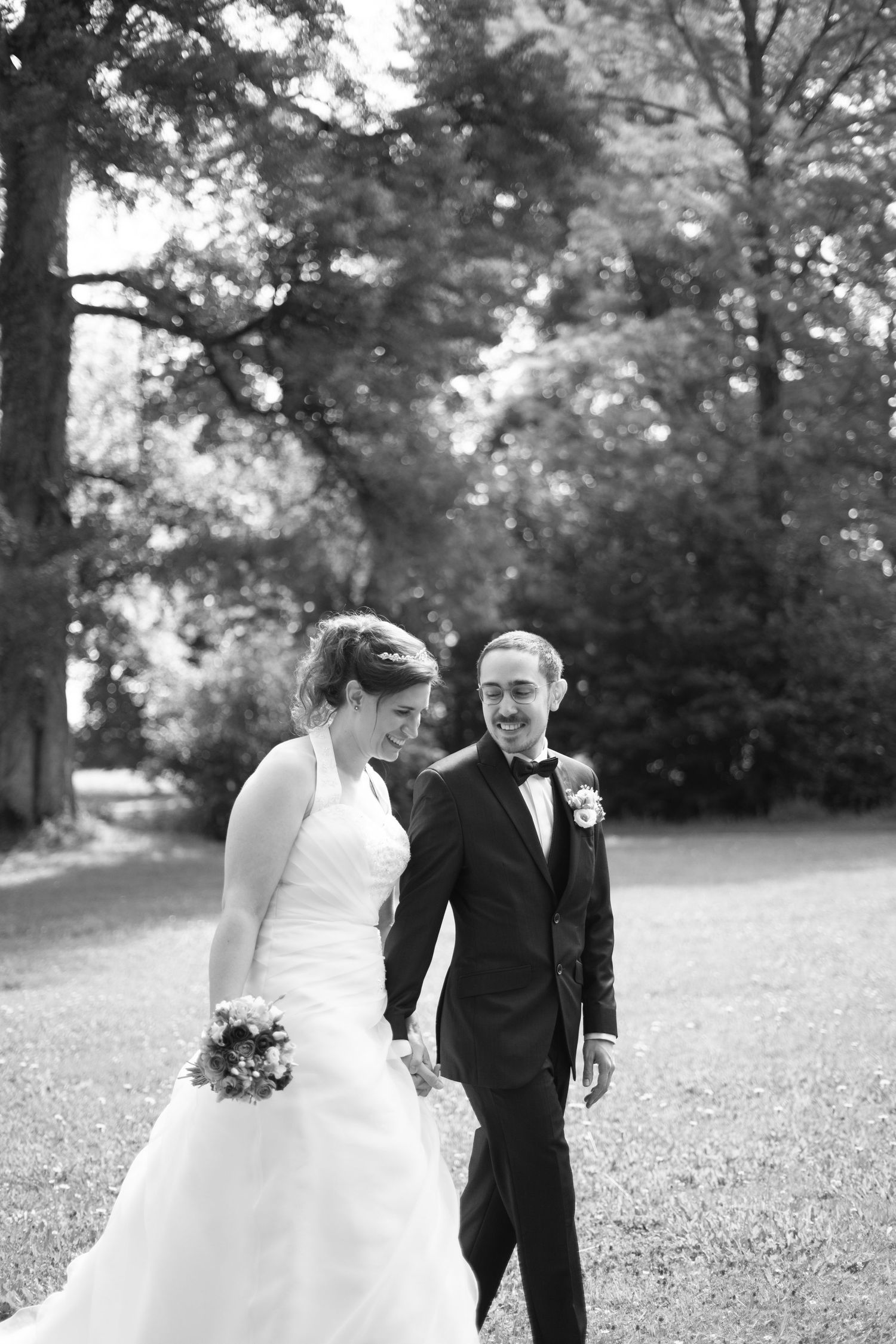 A black and white wedding portrait of a couple sharing a joyful moment outdoors.