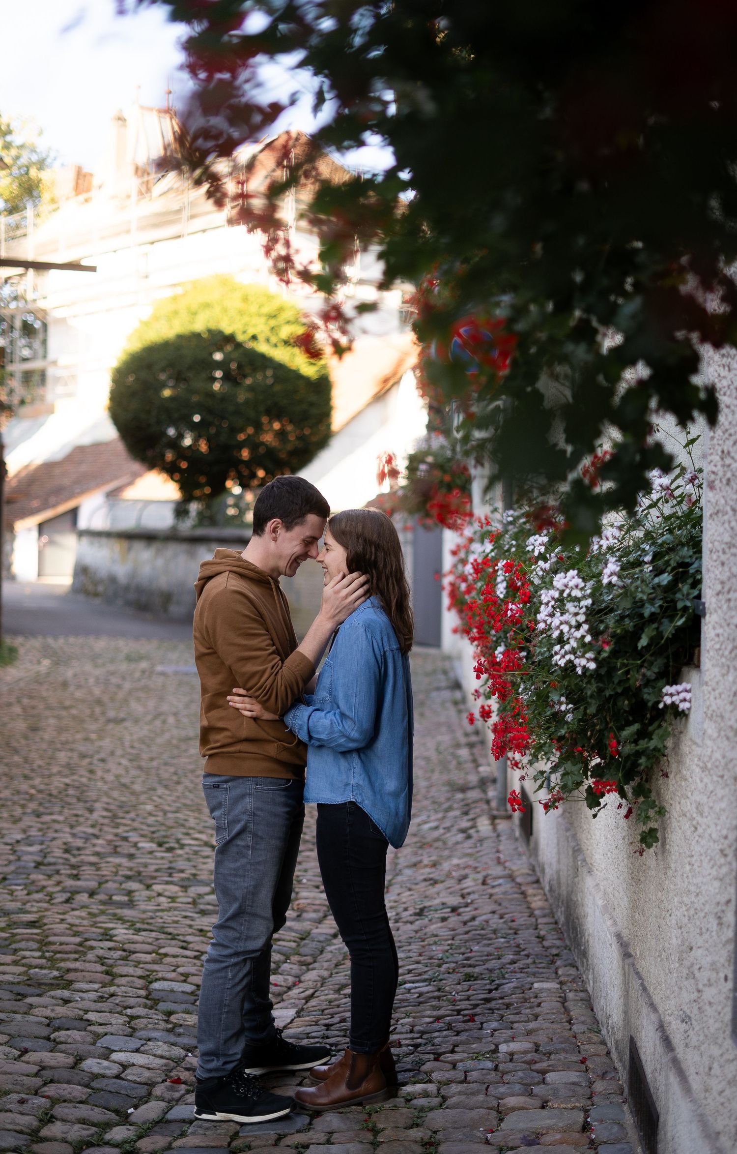 Intimate couple moment on a cobblestone street with flowering vines in the background.