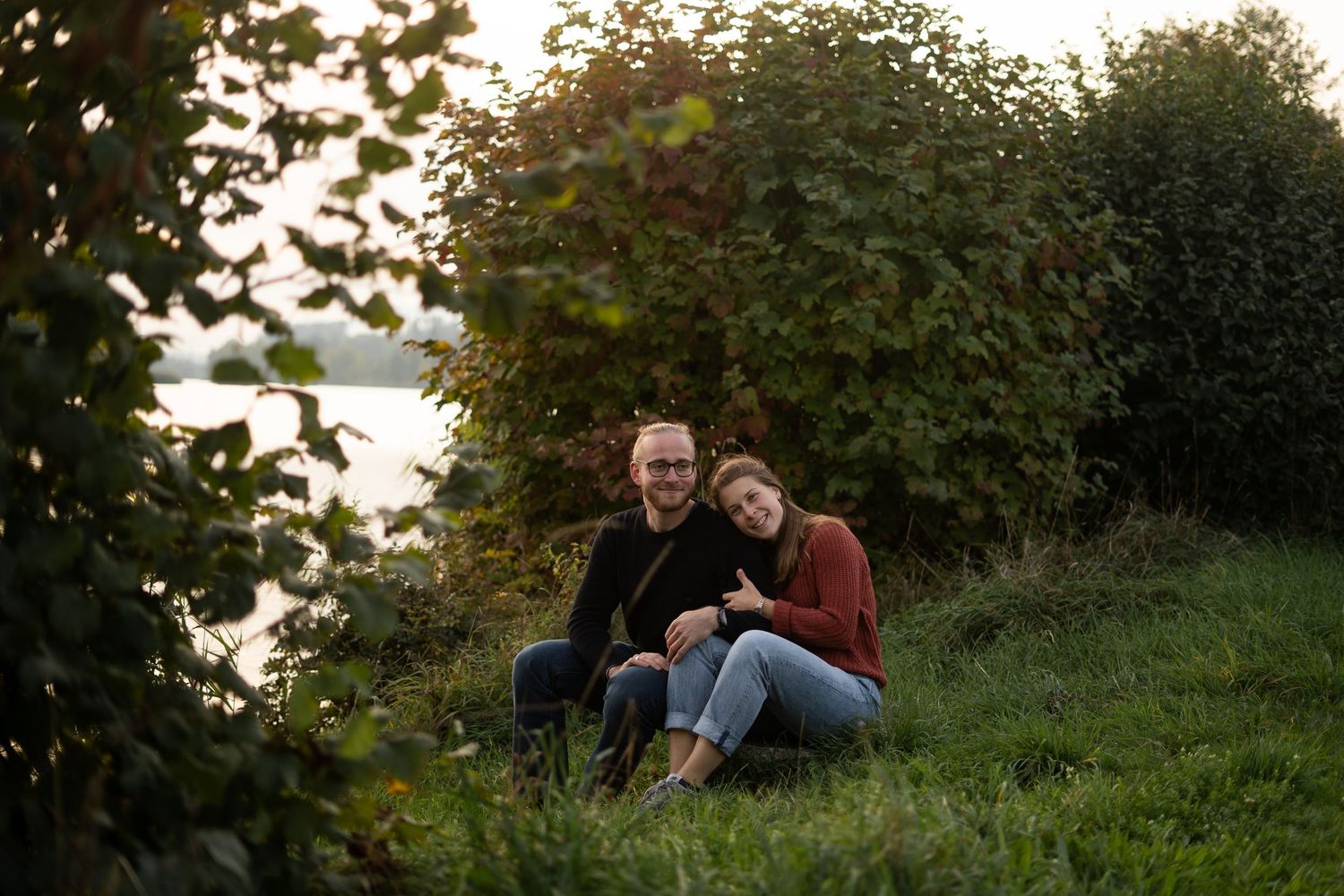 Couple relaxing together on grass during sunset photo session.