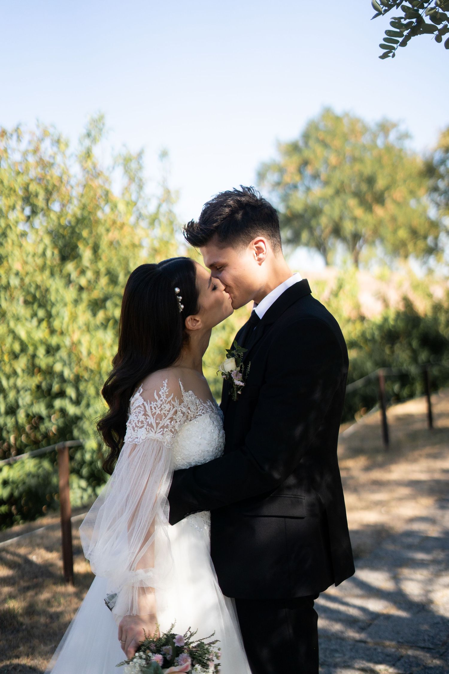An intimate wedding portrait in a sun-dappled garden setting.
