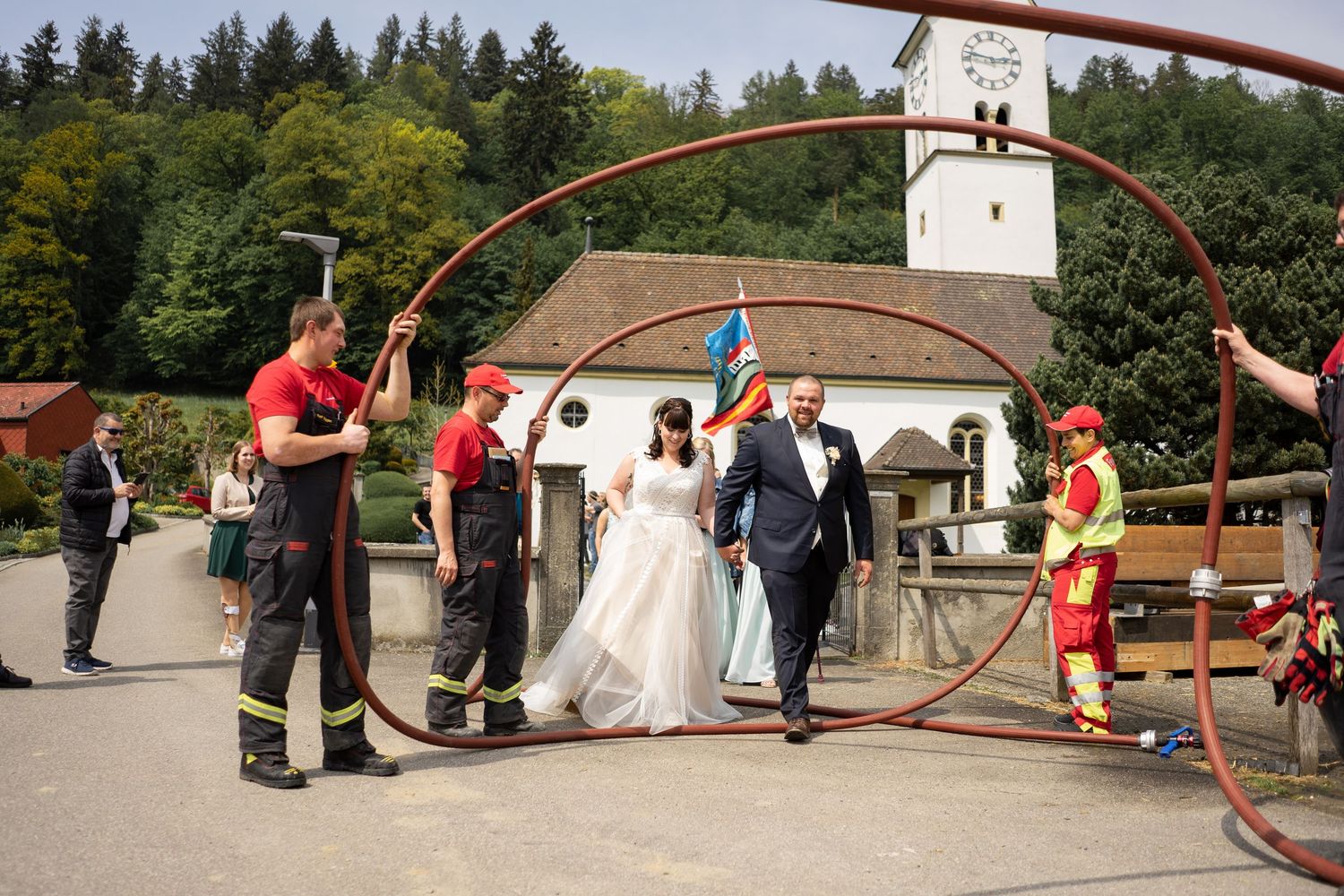 Firefighters create an arch with hoses as newlyweds walk underneath at their wedding ceremony.