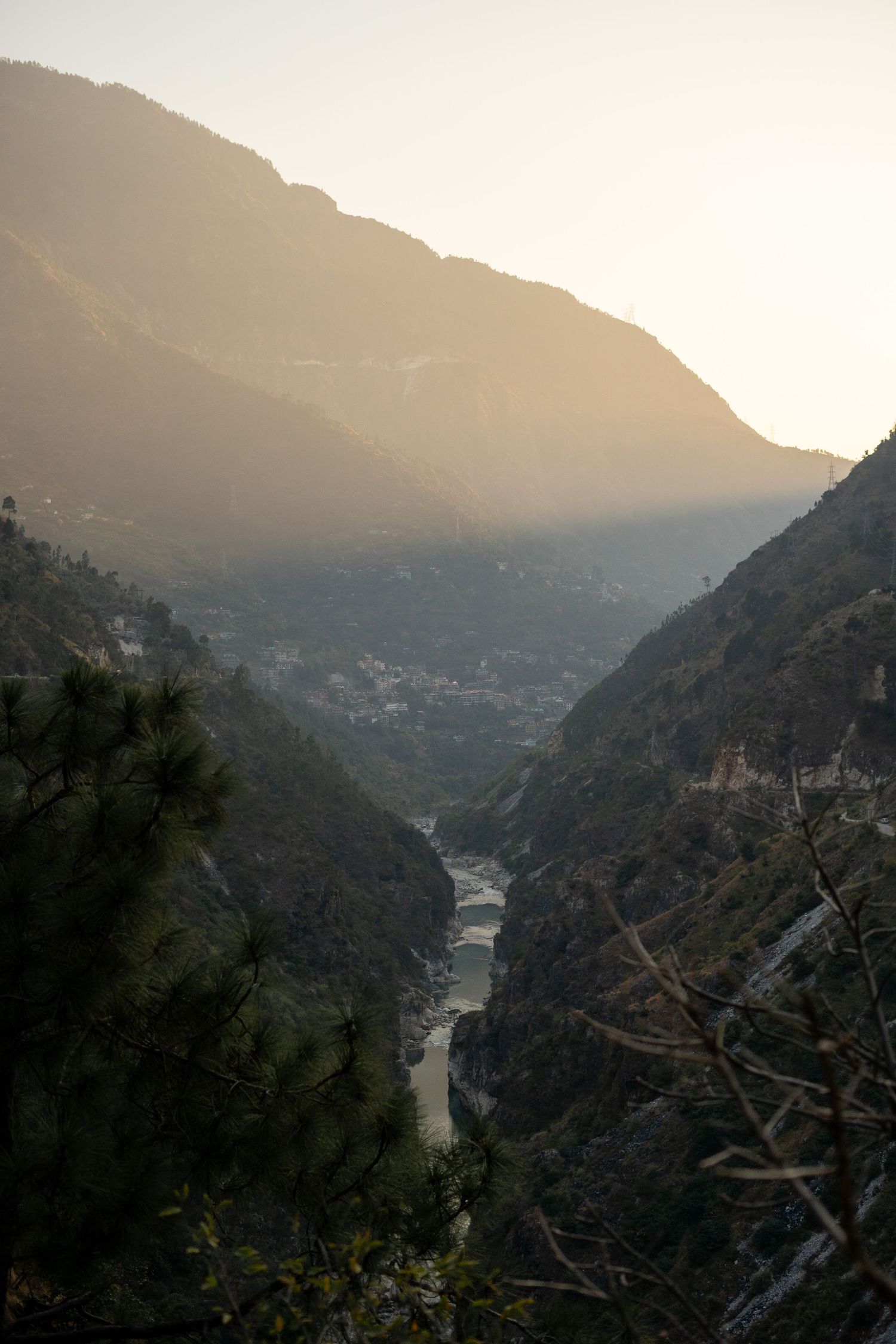 Misty mountain valley view with a winding river cutting through dense forest.