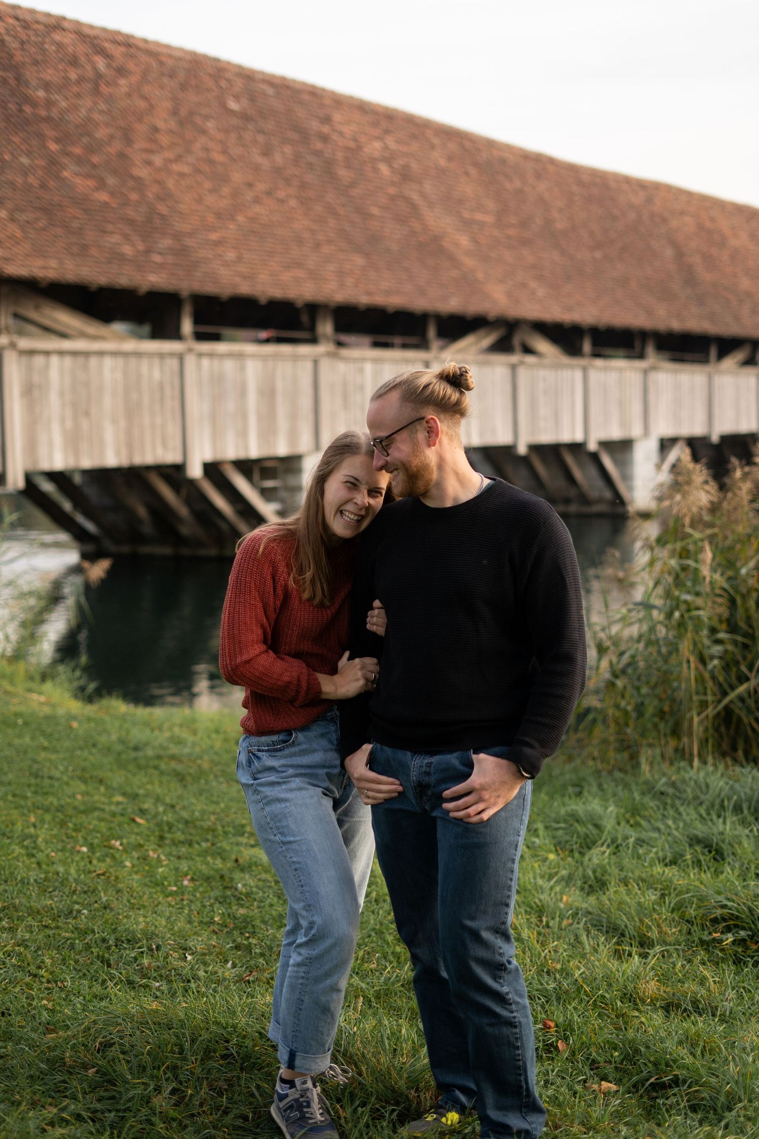 Couple shares tender moment near rustic wooden barn in countryside setting.