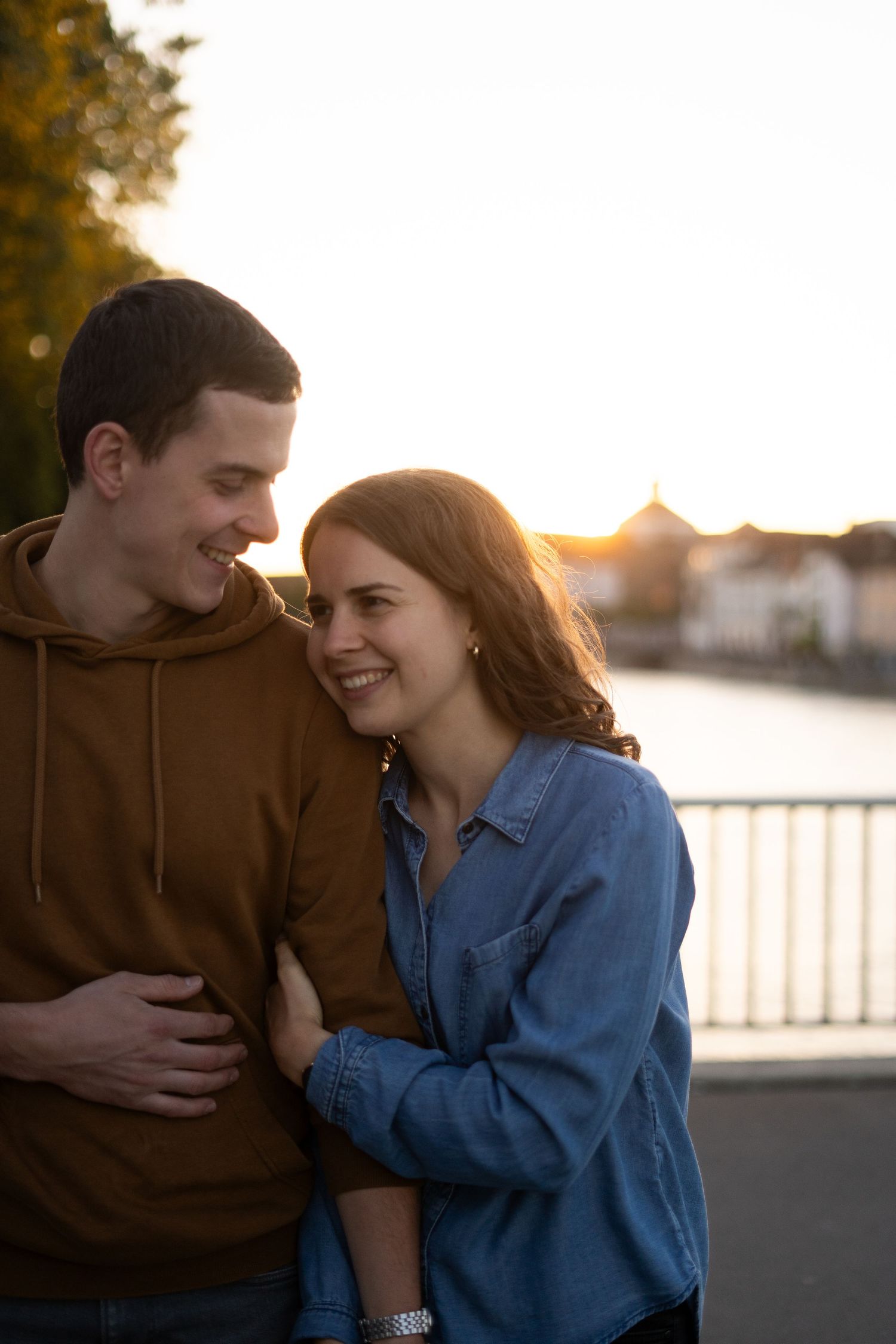 Candid moment of laughter and love during sunset by the waterfront.