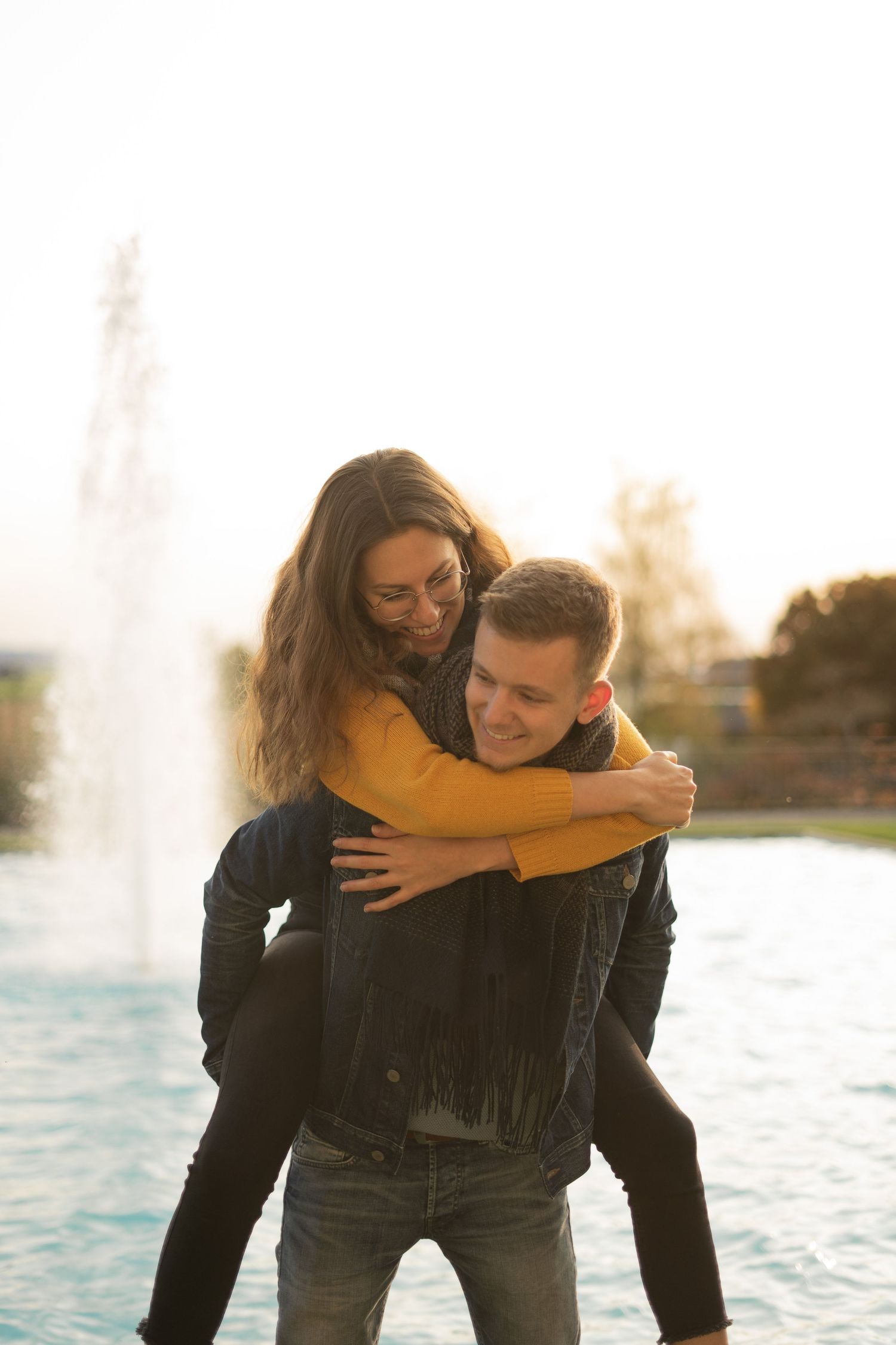 A playful piggyback ride near a fountain at sunset.