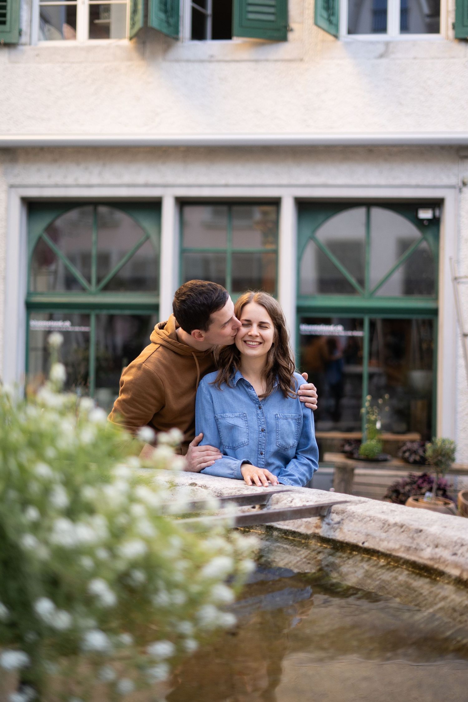 Sweet couple moment by a fountain with charming European architecture in background.