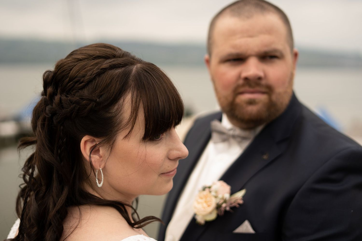 Close-up wedding portraits captured by the water on an overcast day.