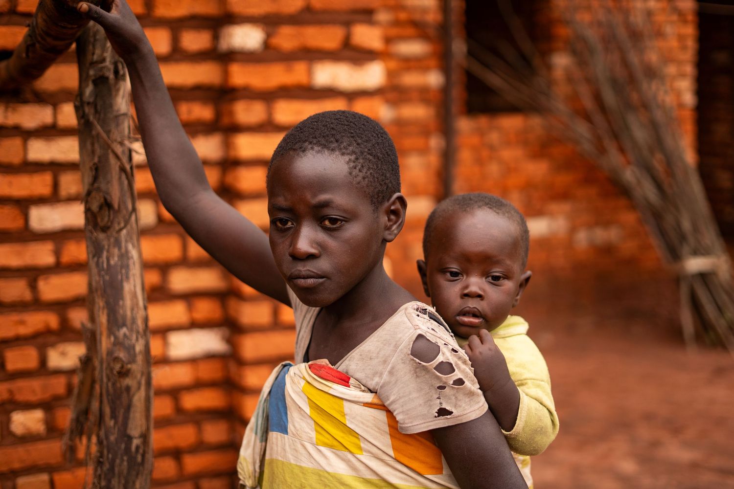 Children playing near red brick walls in an outdoor setting.