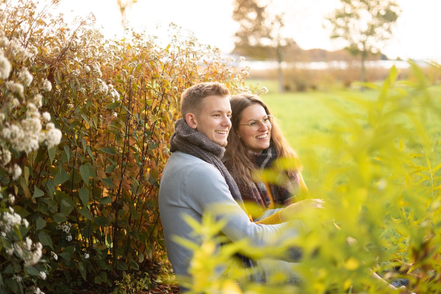Romantic couple embraces in golden autumn foliage at sunset in park.