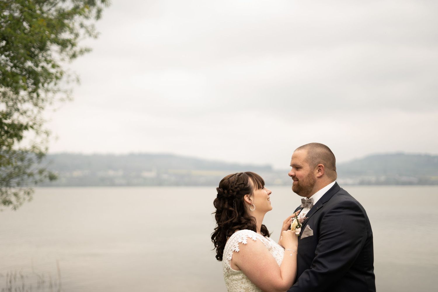 Scenic lakeside wedding photos with mountains, water, and natural grass in the foreground.