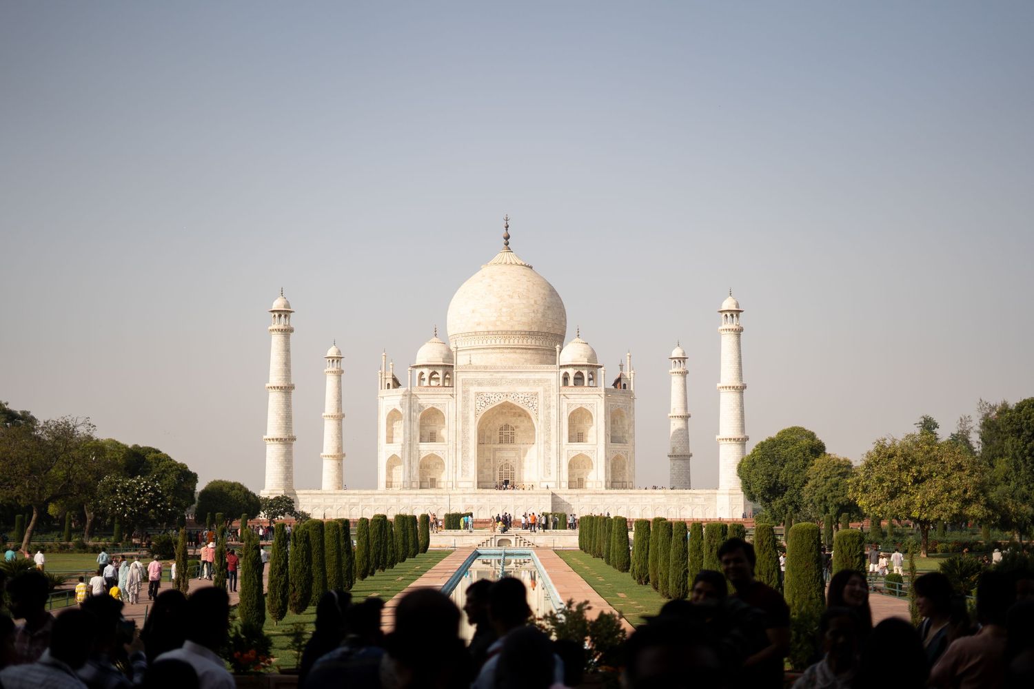 The majestic Taj Mahal in daylight with its reflecting pools and manicured gardens.