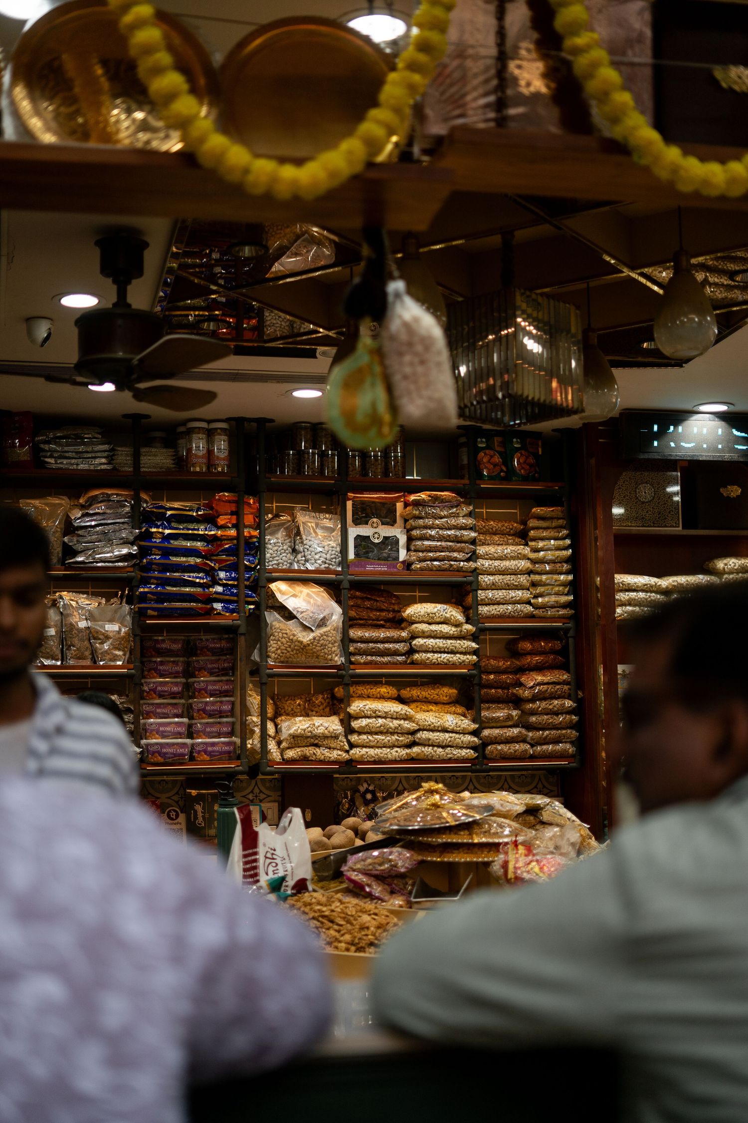 Stacks of folded textiles and fabrics displayed in a dimly lit market shop.