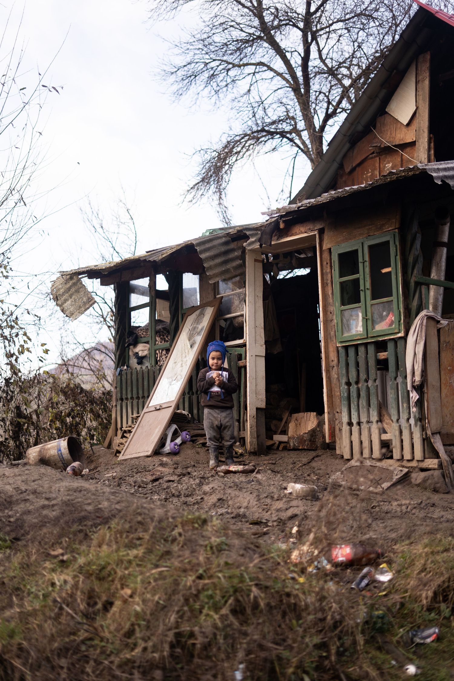 A dilapidated wooden shack with broken windows and debris scattered around the entrance.