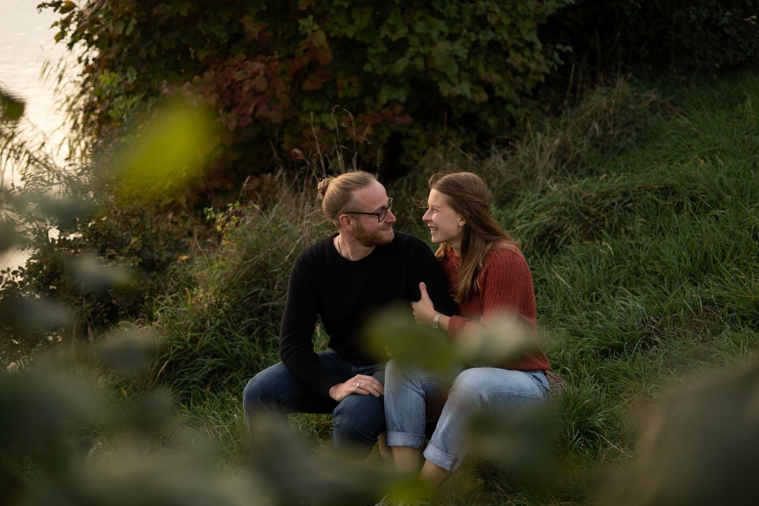 Intimate couple portrait session in lush green outdoor setting.