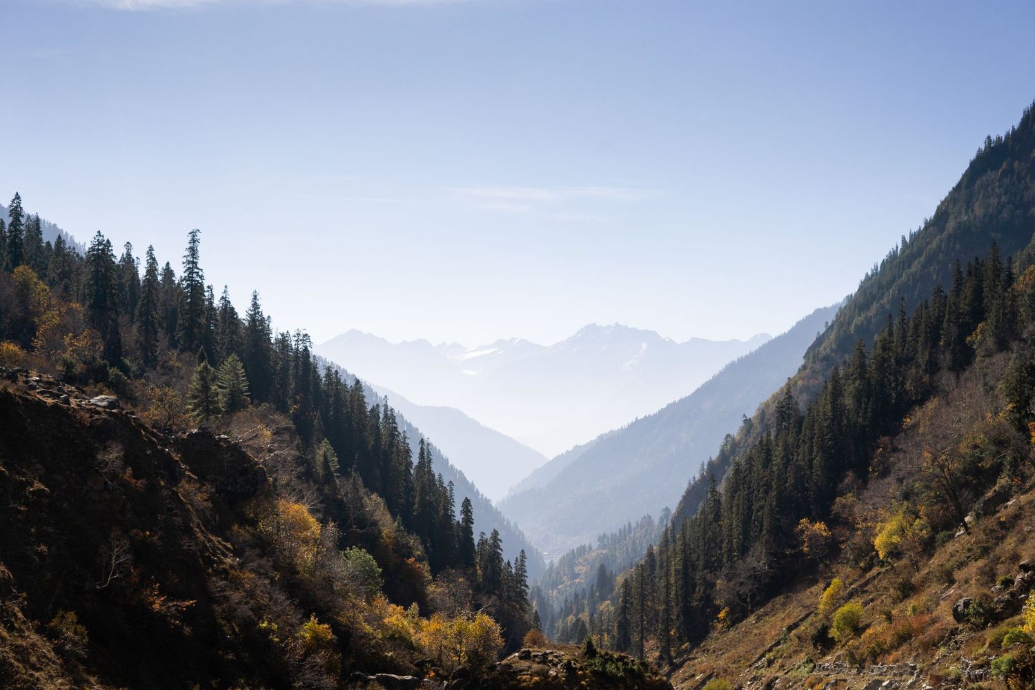 Scenic mountain valley with autumn colors and layered peaks stretching into the distance.