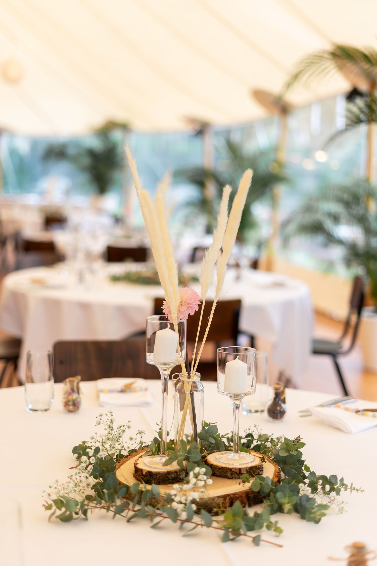 Wedding reception table decor with rustic wood slices, greenery garlands and candlesticks.