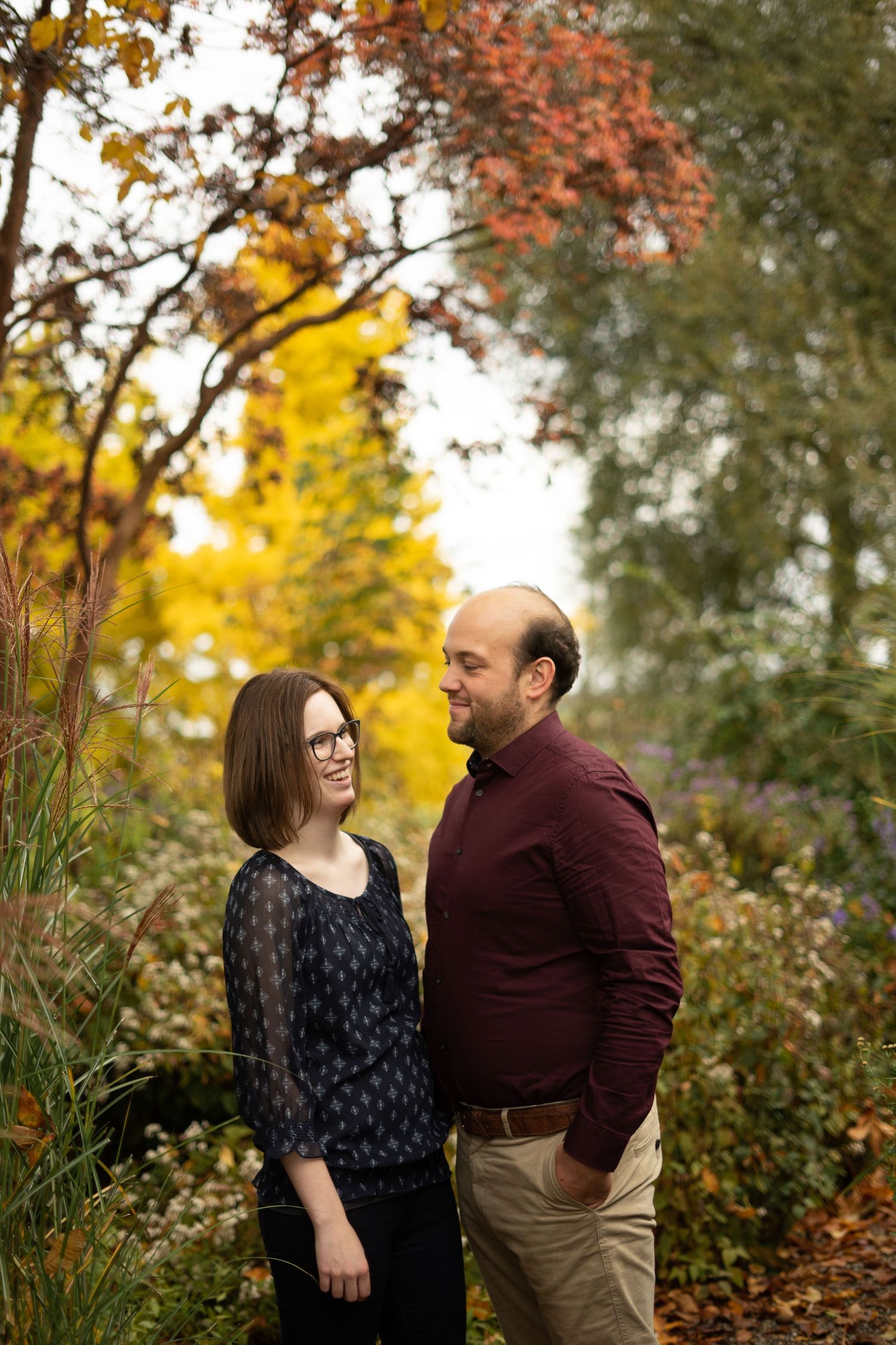 A tender moment shared between a couple surrounded by colorful autumn trees and foliage.