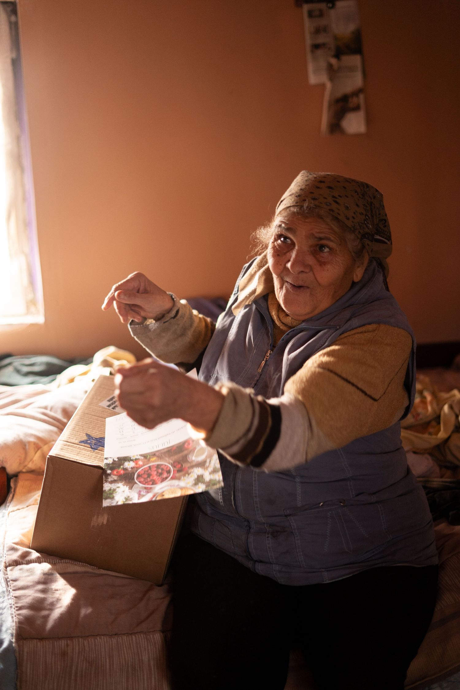 A person opening a package while sitting on a couch in warm natural lighting.