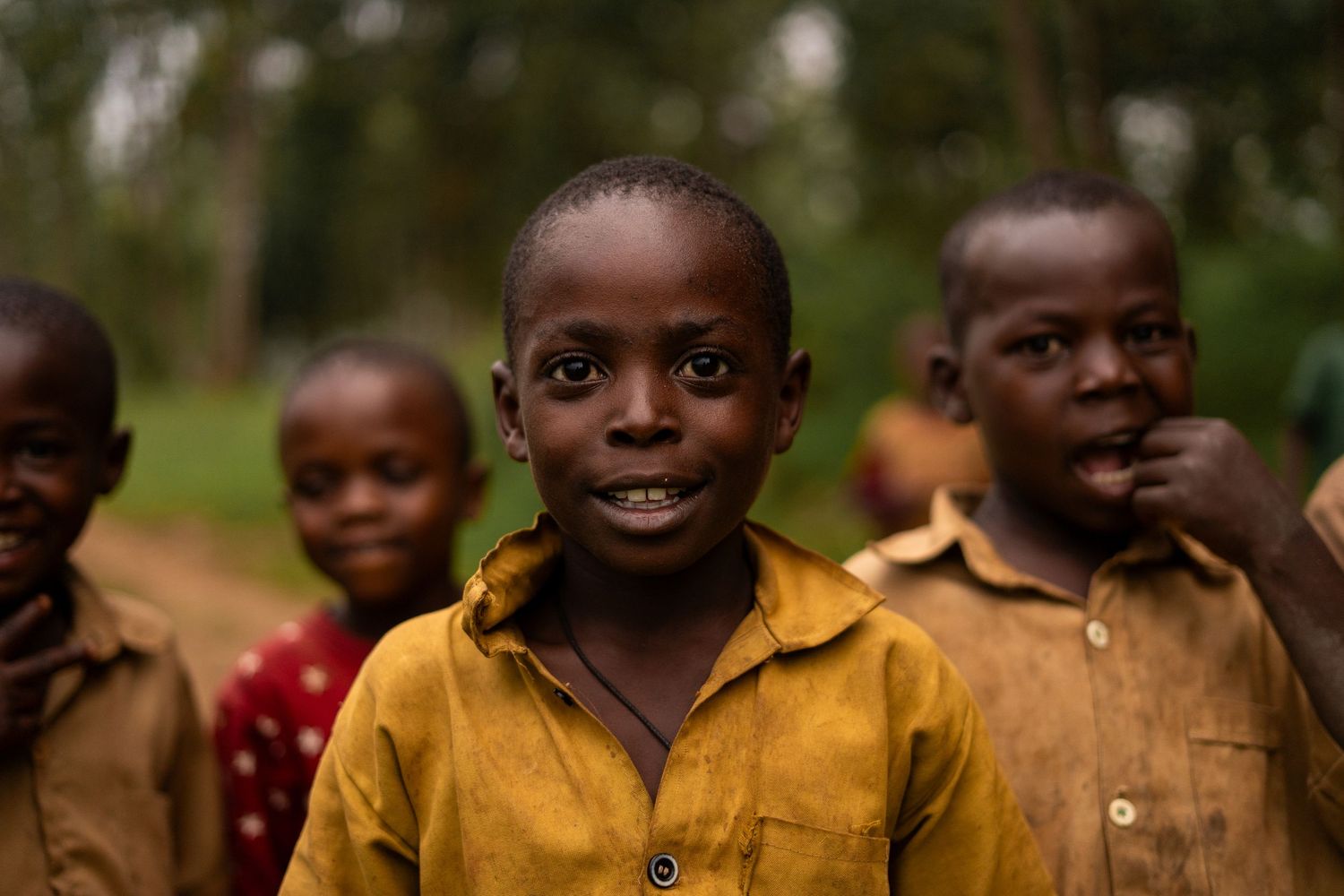 Young children in colorful shirts smiling outdoors.