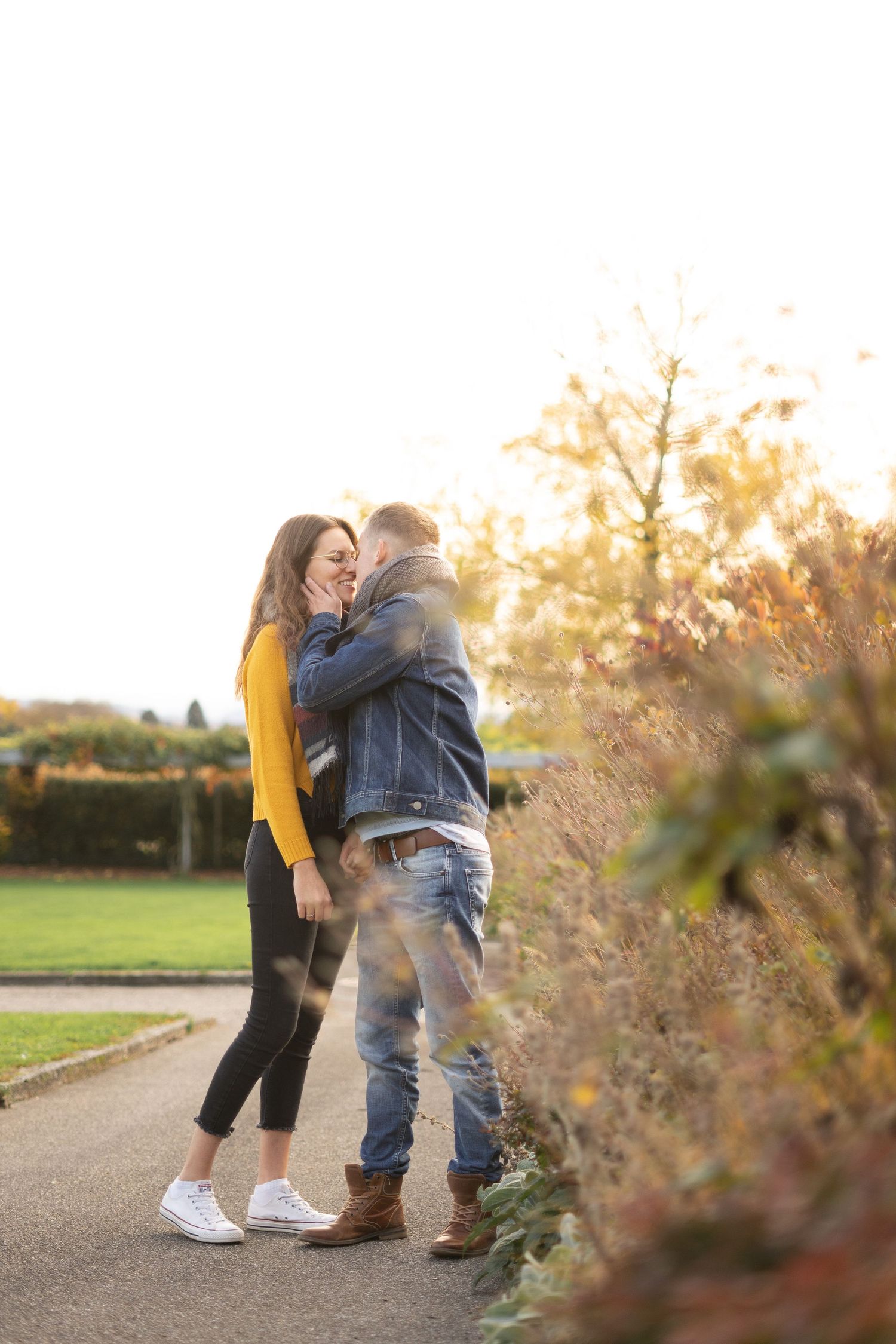 A joyful couple embracing on a path during golden hour with autumn foliage in the background.