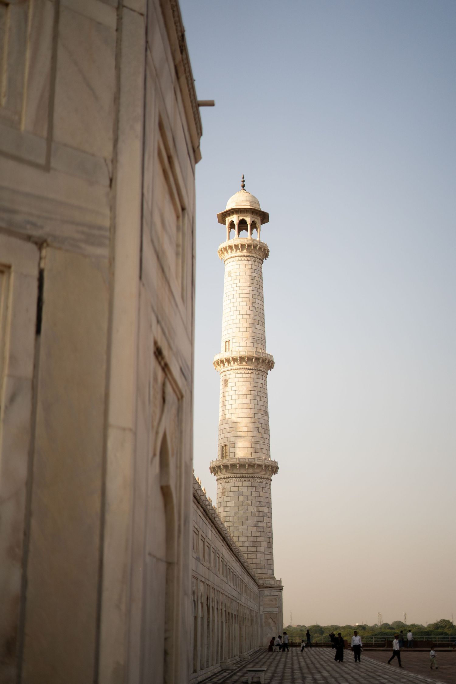 White marble minaret of the Taj Mahal rises against a clear sky.
