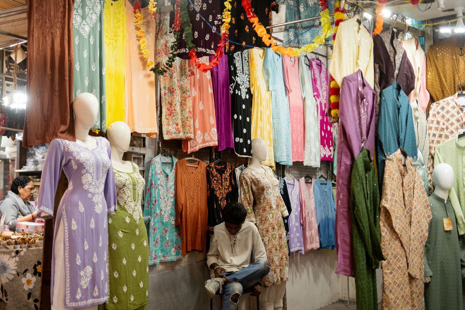Colorful traditional clothing and textiles hanging on display in a market.