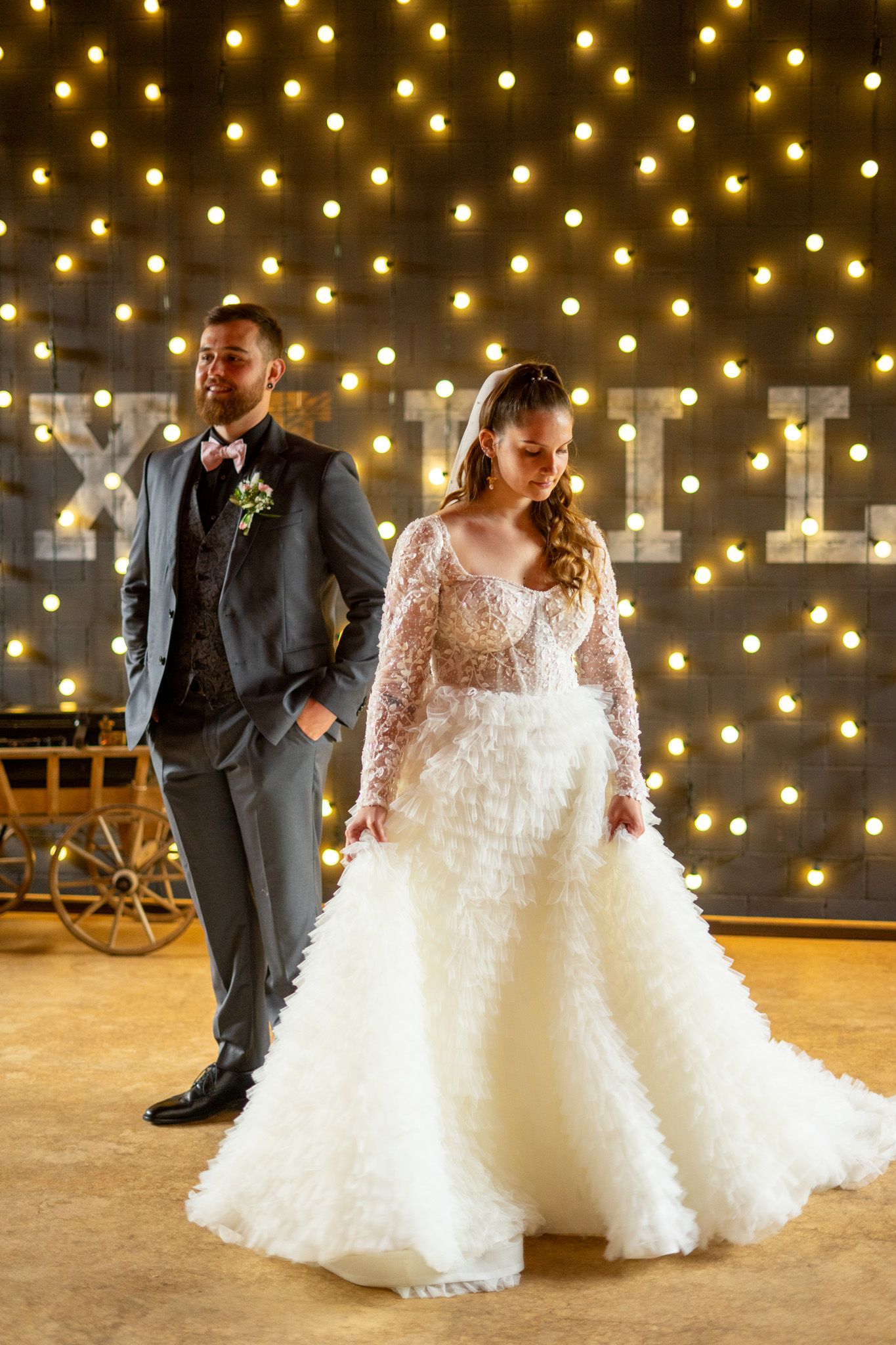Wedding portraits with stunning string light backdrop showcasing bride's flowing white gown.