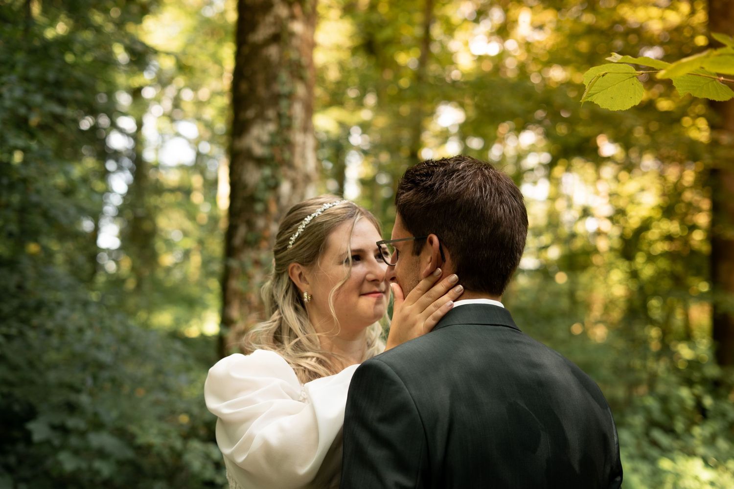Intimate forest wedding moment captured with golden sunlight filtering through trees.