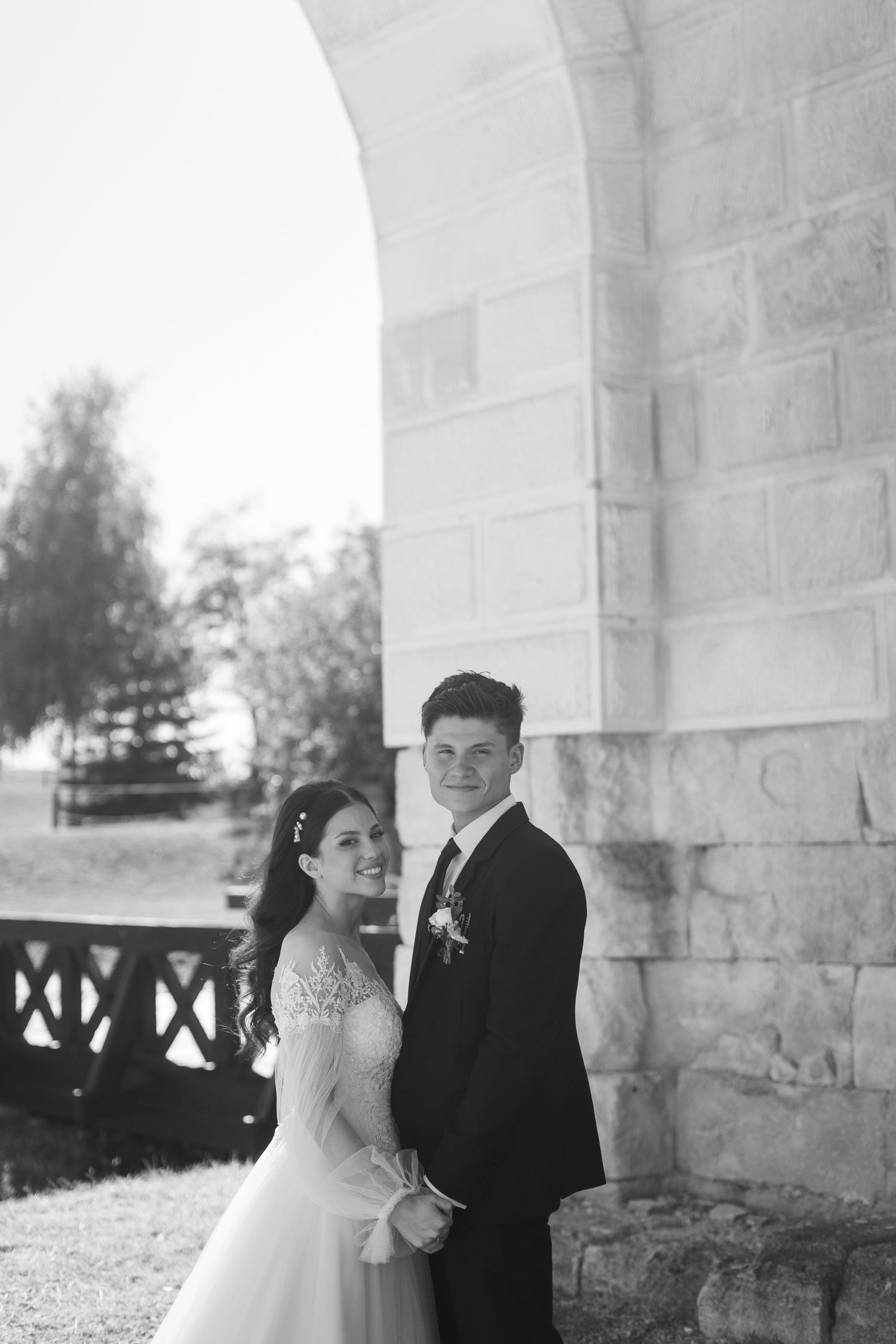 A romantic wedding photo sequence showing tender moments between a couple under stone archways.