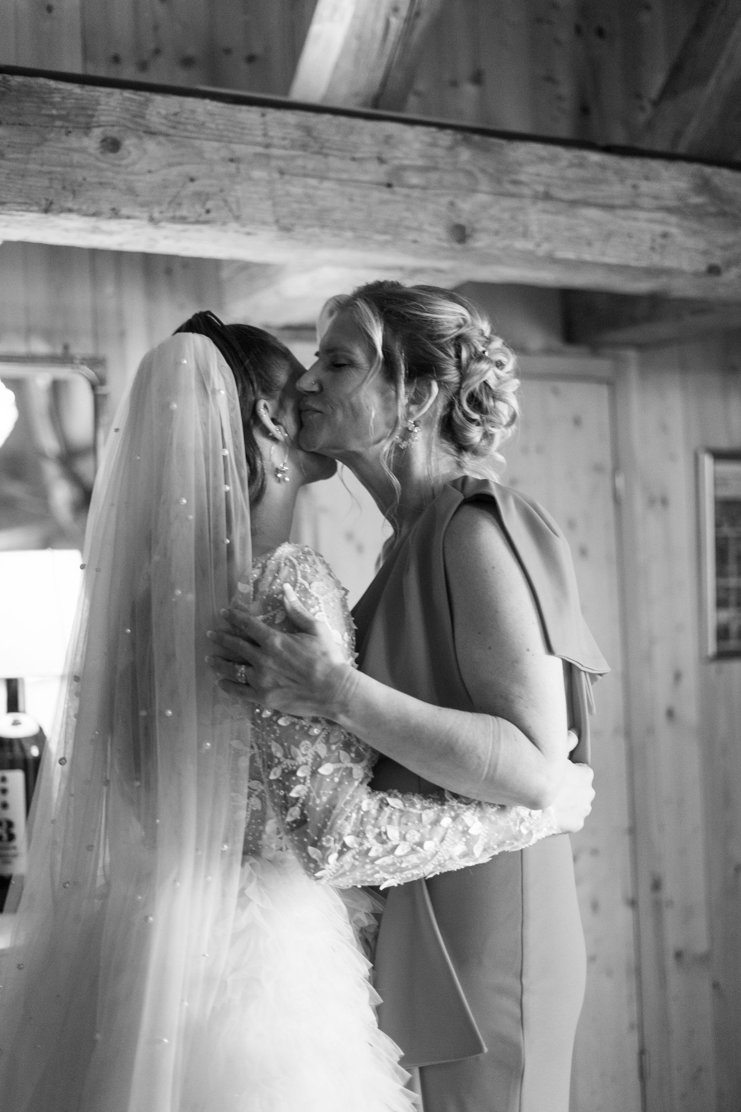 Emotional embrace captured in black and white at rustic wedding venue.