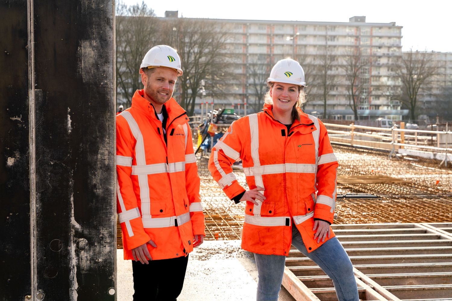 Construction workers in high visibility safety gear inspect building materials at a construction site. - Noelle Schmeltz Fotografie
