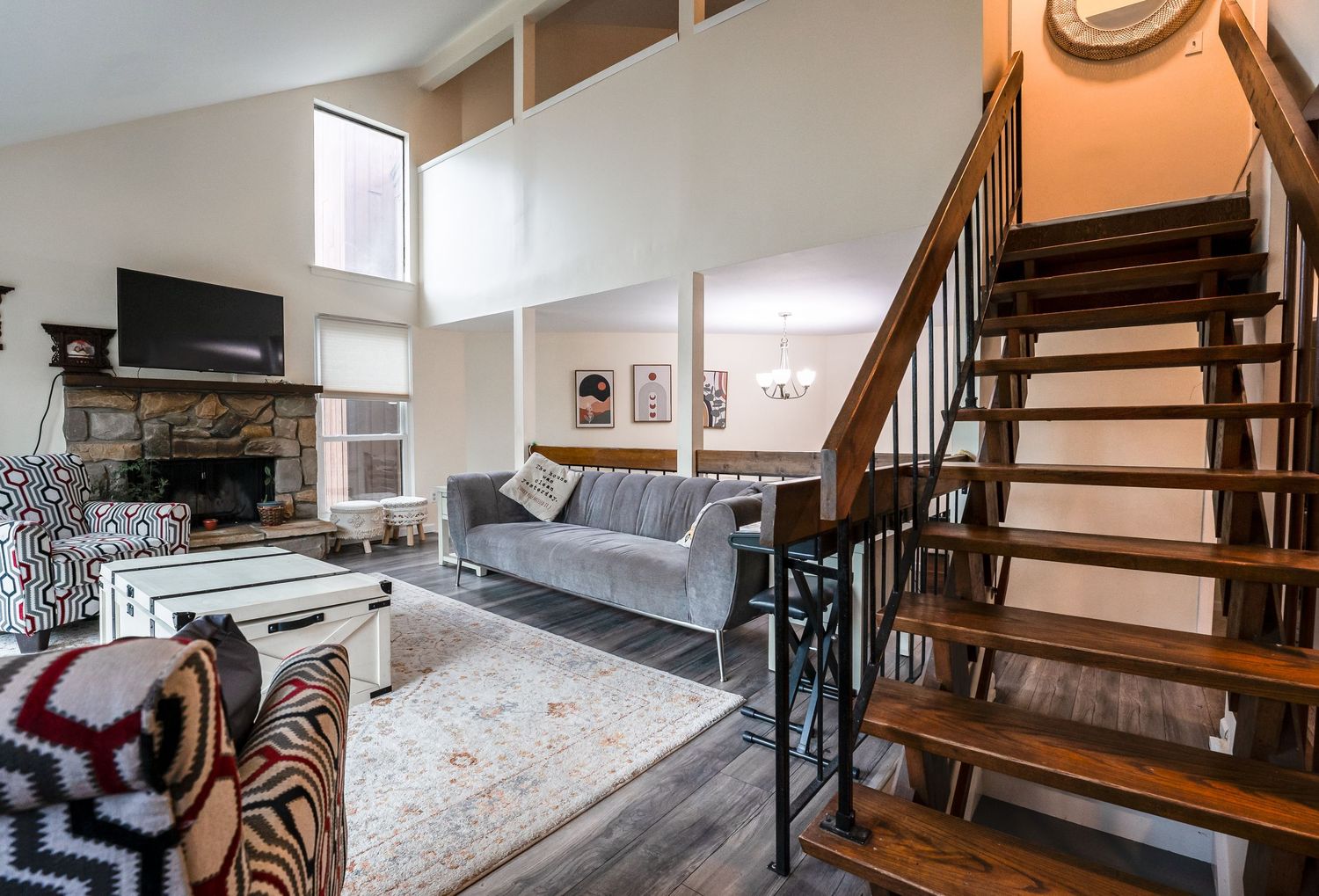 Modern spiral staircase with wooden treads and white walls leads up to a lofted area in a stylish apartment interior.