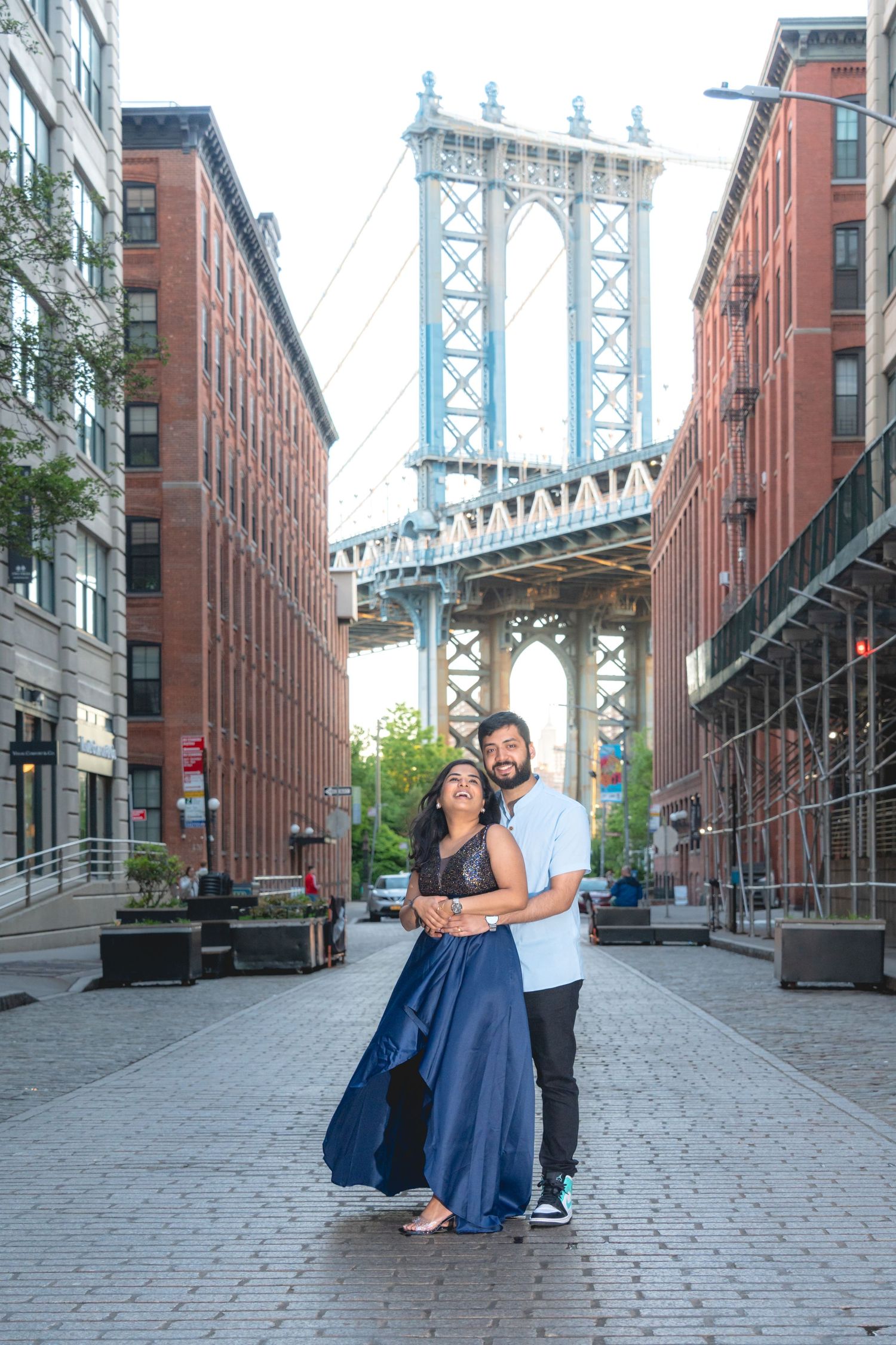Series of romantic poses on DUMBO cobblestone street with Manhattan Bridge view.