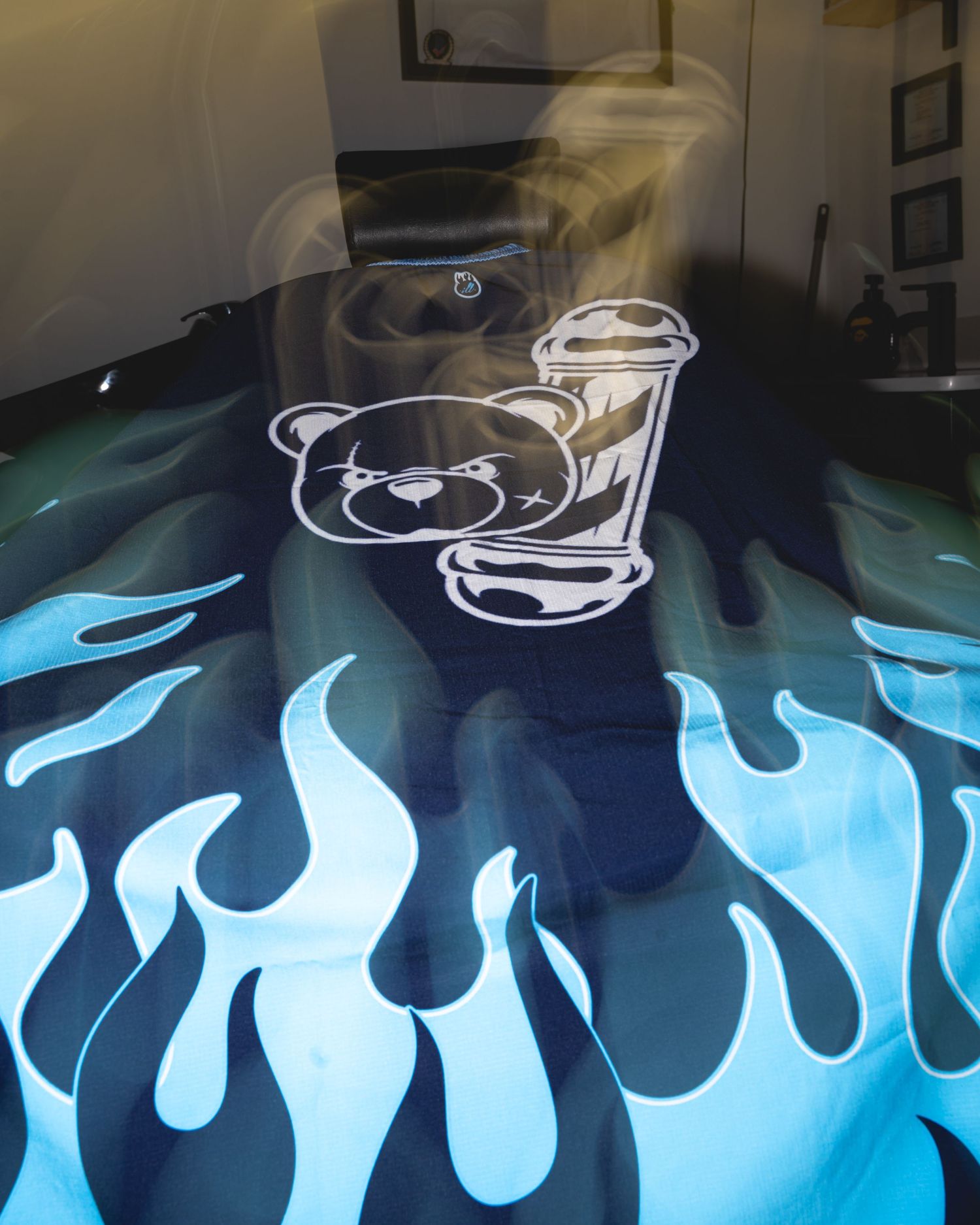 Black t-shirt with cartoon teddy bear logo and blue flame design graphics.