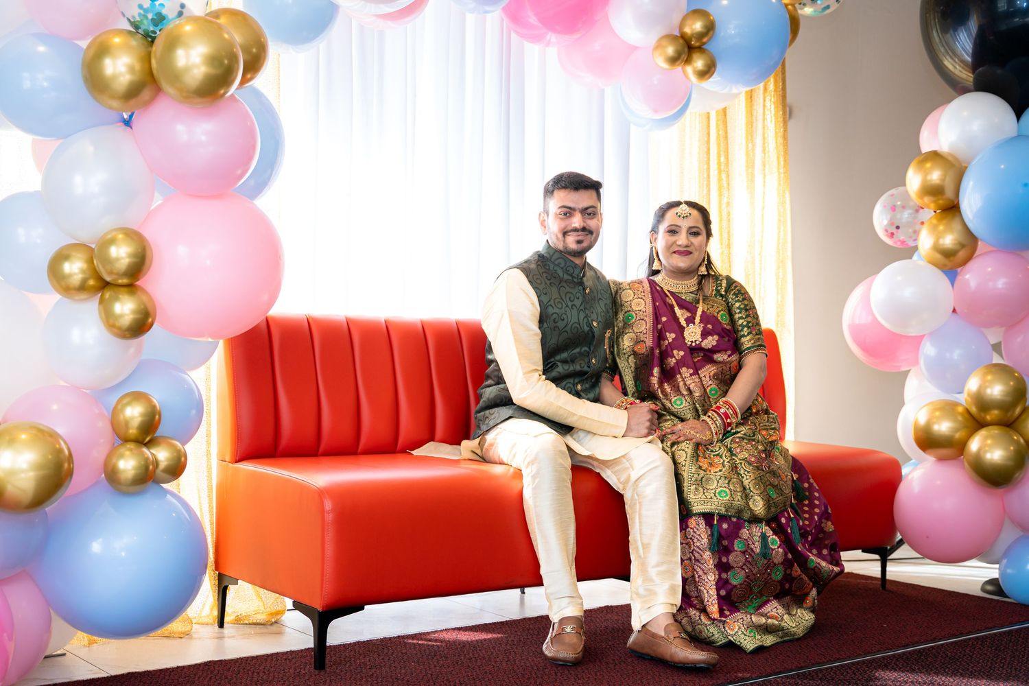 Party setup with pink and blue balloons, red couch, and gold accents.