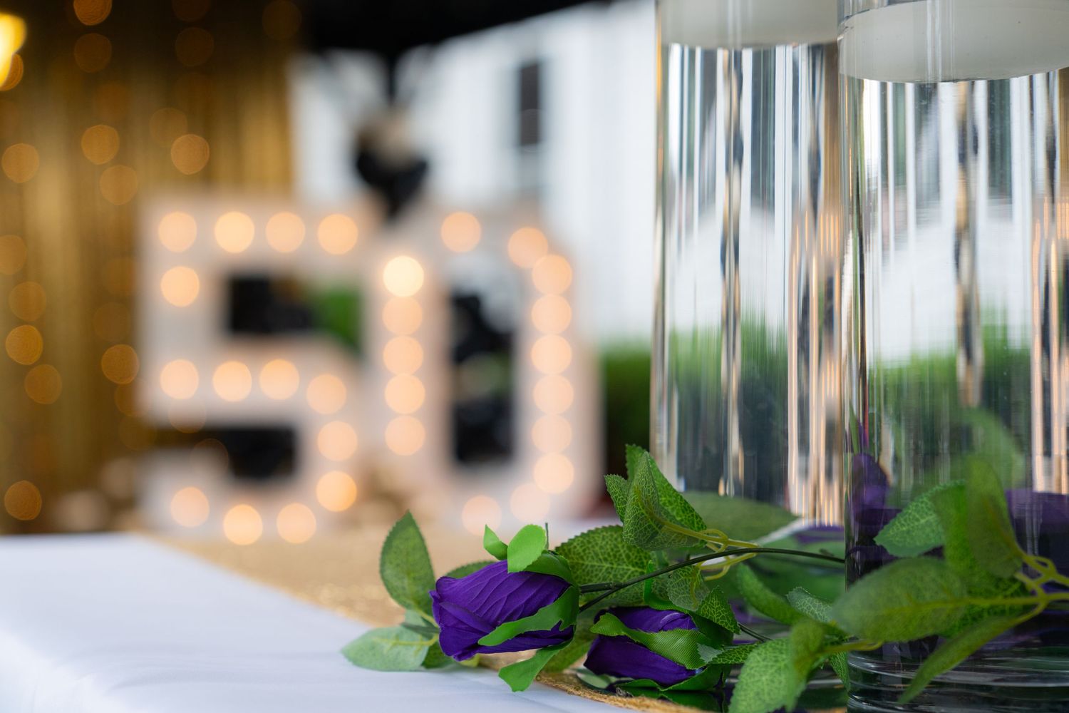 Purple and green floral decorations adorn a glass vase centerpiece at an elegant event setting.