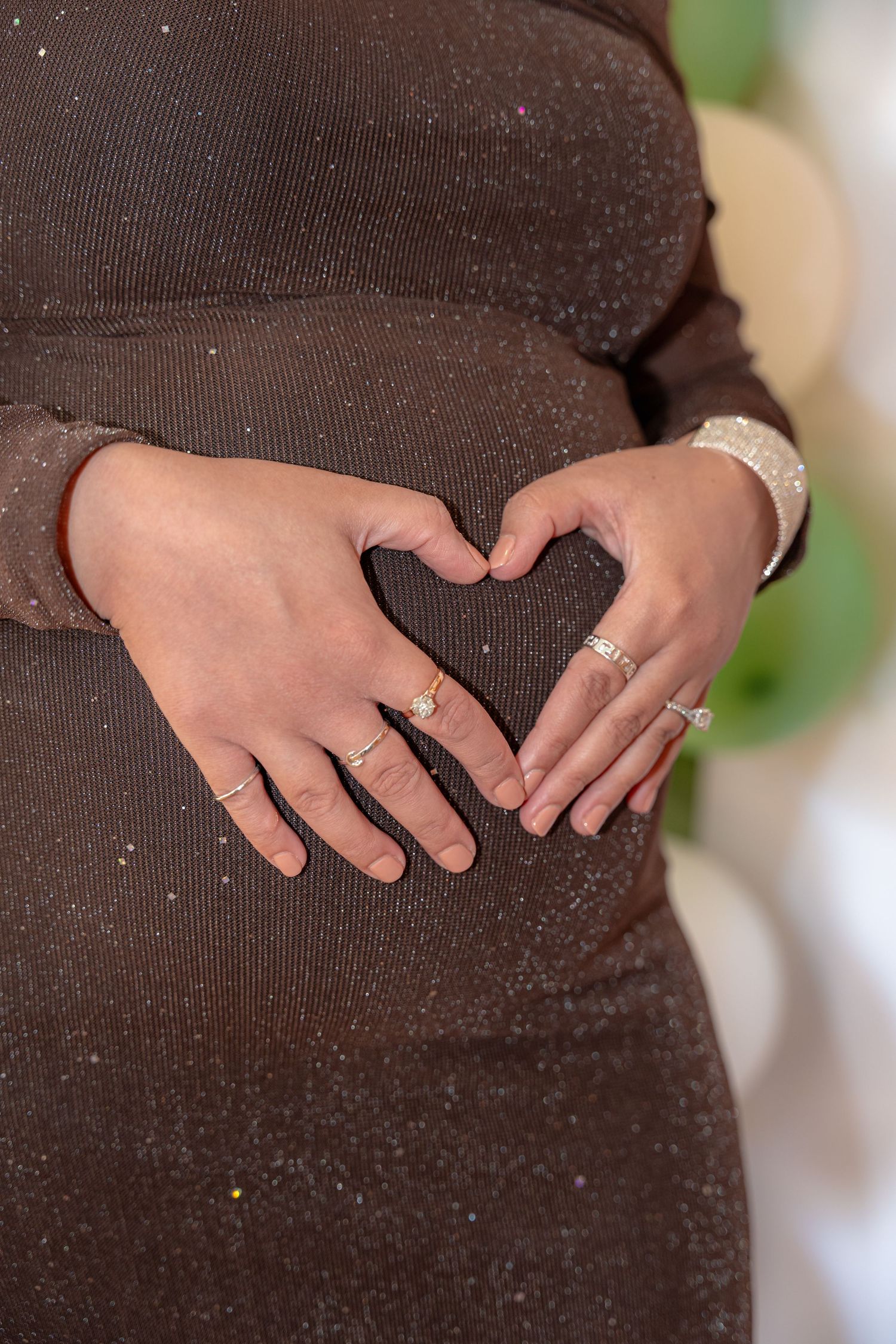 Close-up sequence showing hands wearing rings and jewelry against a dark brown sweater background.