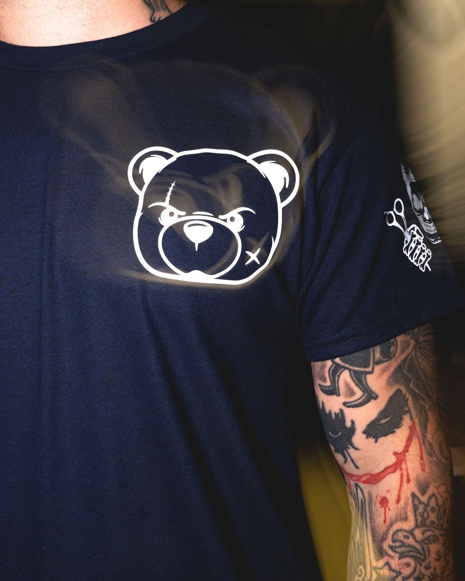 Dark t-shirt with minimalist white bear face logo design shown from different angles.