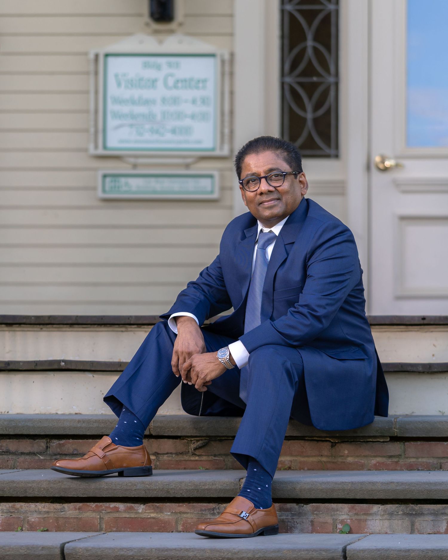 Professional in blue suit sitting on steps of historic building entrance.