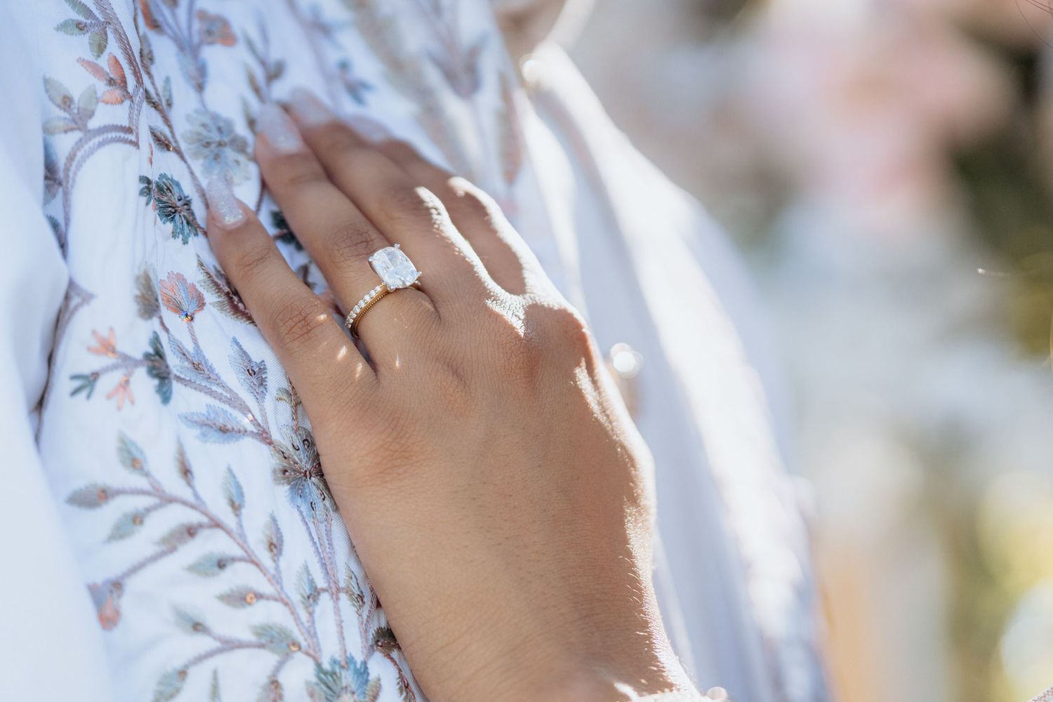 Detail shots of an engagement ring with diamond solitaire against floral fabric.